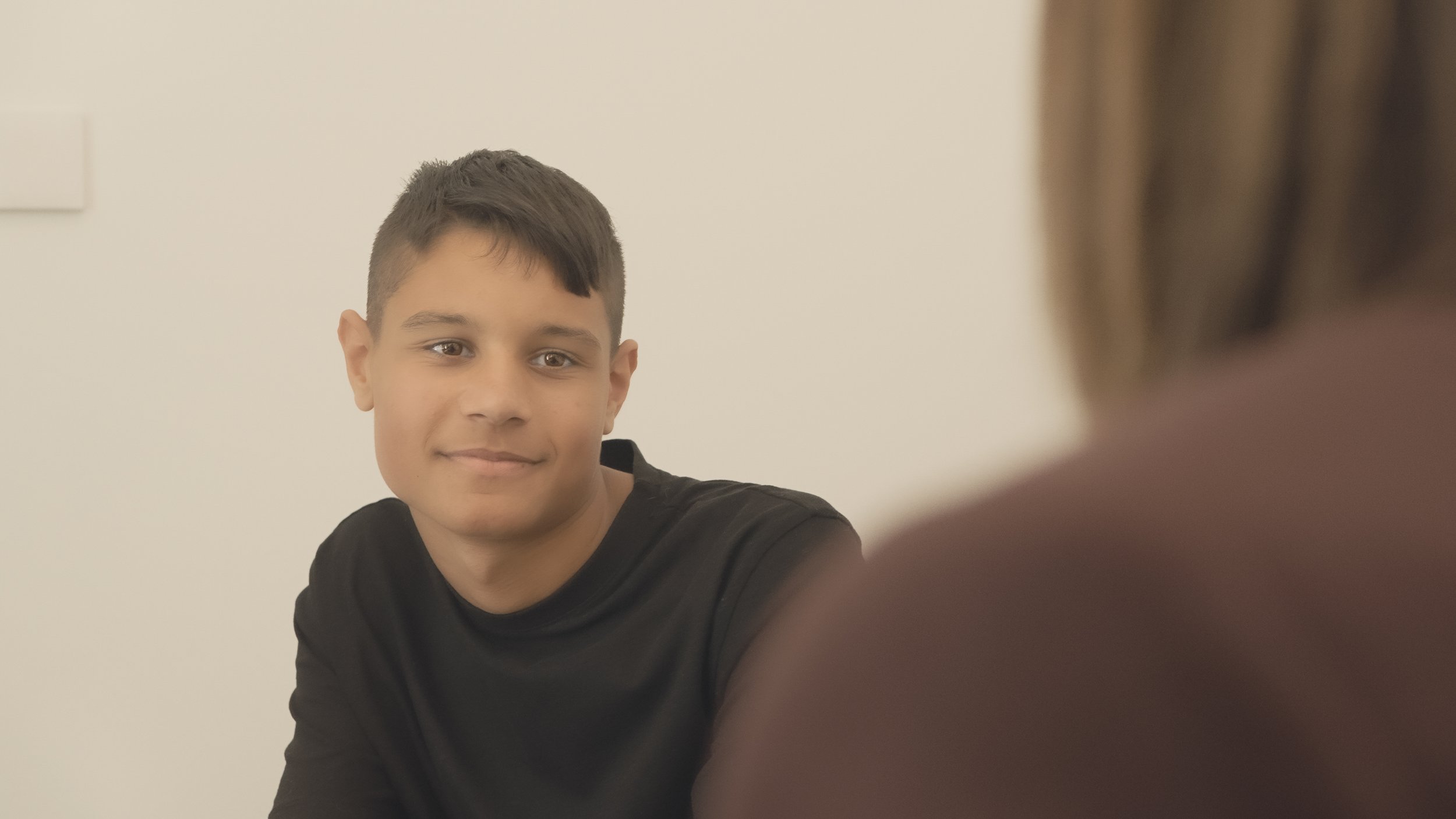 A teenager speaking with an adult in a therapy setting.