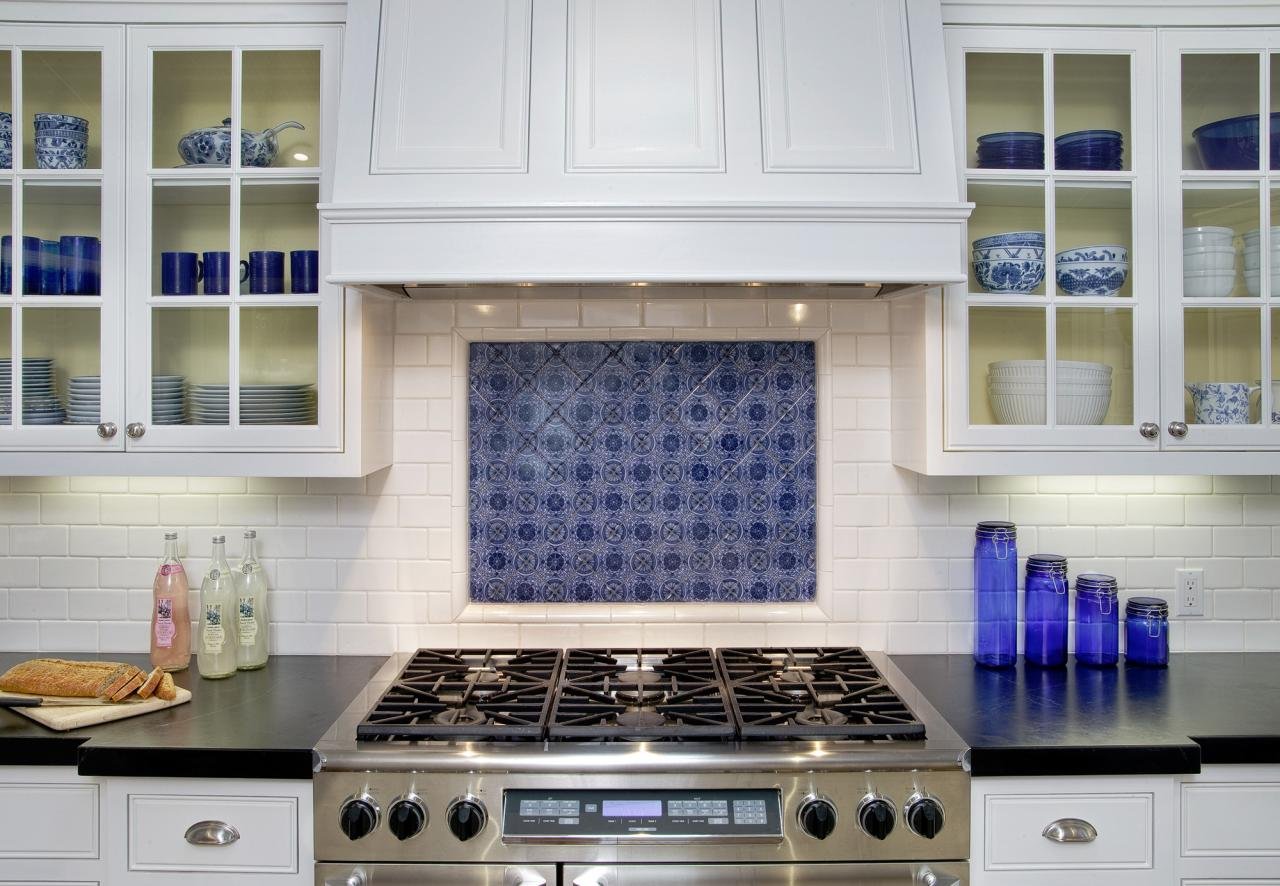 THE RANGE HAS A CUSTOM HOOD AND IS SURROUNDED BY FLUSH, INSET CABINETS WITH VINTAGE HARDWARE.