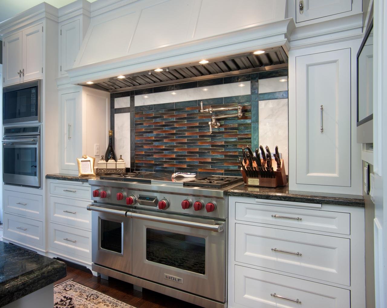 THE KITCHEN’S WOLF RANGE, BACKED BY BASKET WEAVE GLASS TILES, SITS UNDER A CUSTOM HOOD.