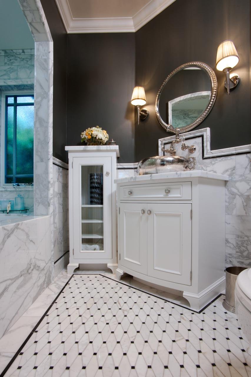 THE GUEST BATHROOM HAS MARBLE WAINSCOTING, CROWN MOLDING, CLASSIC DECORATIVE TILE ON THE FLOOR AND A VESSEL SINK.