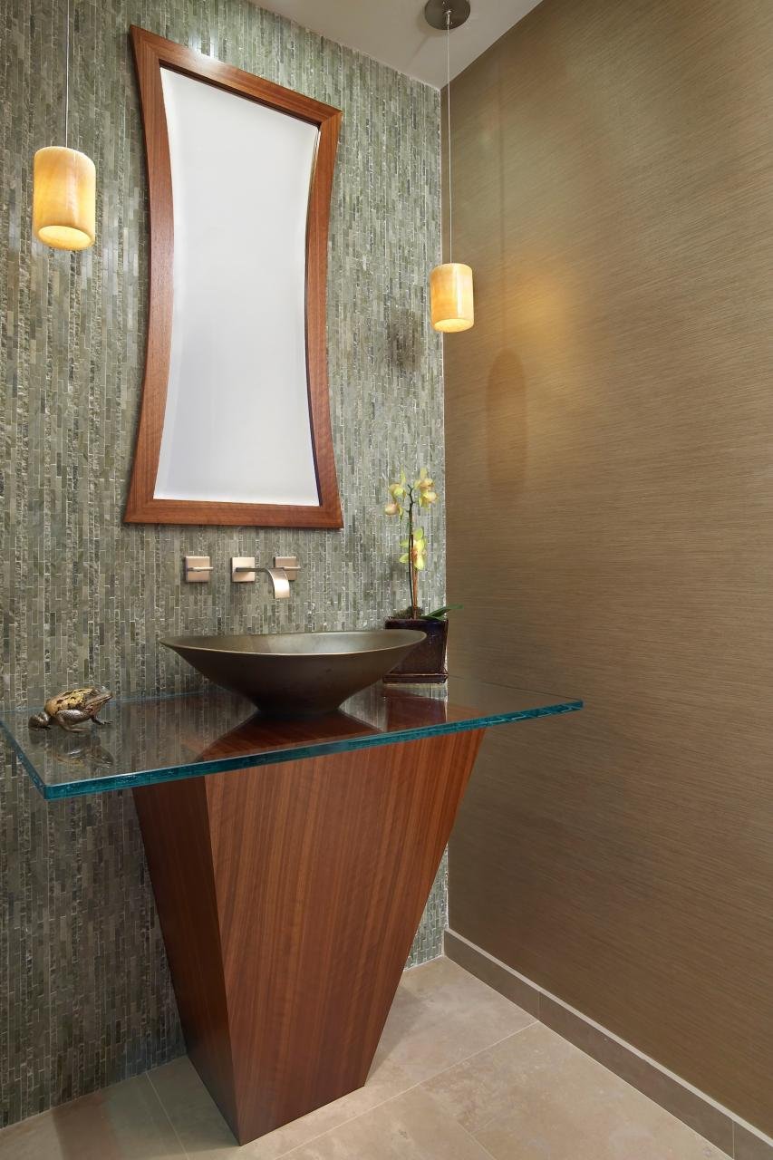 THE GUEST BATHROOM HAS A CUSTOM CABINET AND GLASS TOP WITH VESSEL SINK.