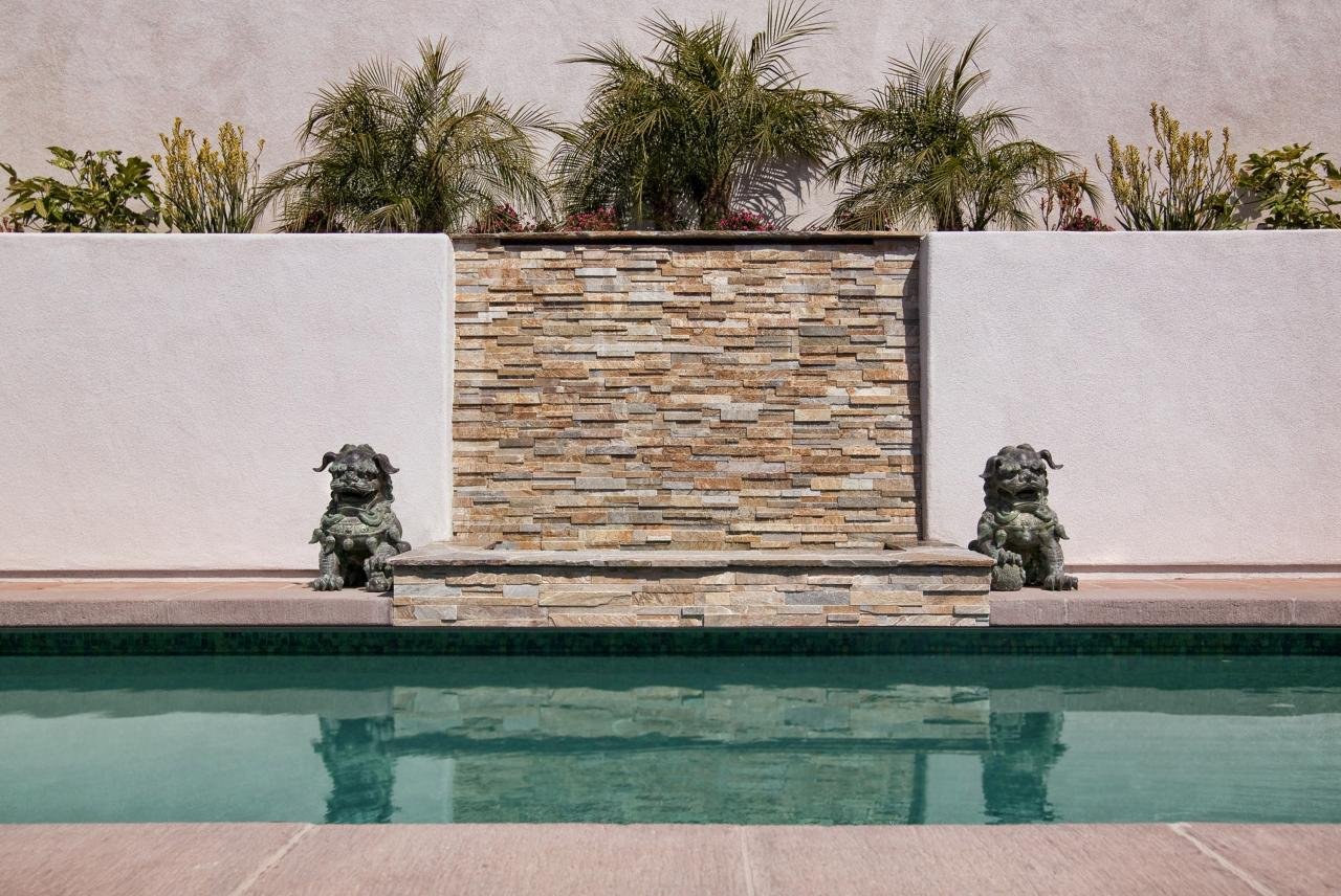 THE POOL FEATURES A STONE WATERFALL AND PEBBLE-SHEEN FINISH TILES.