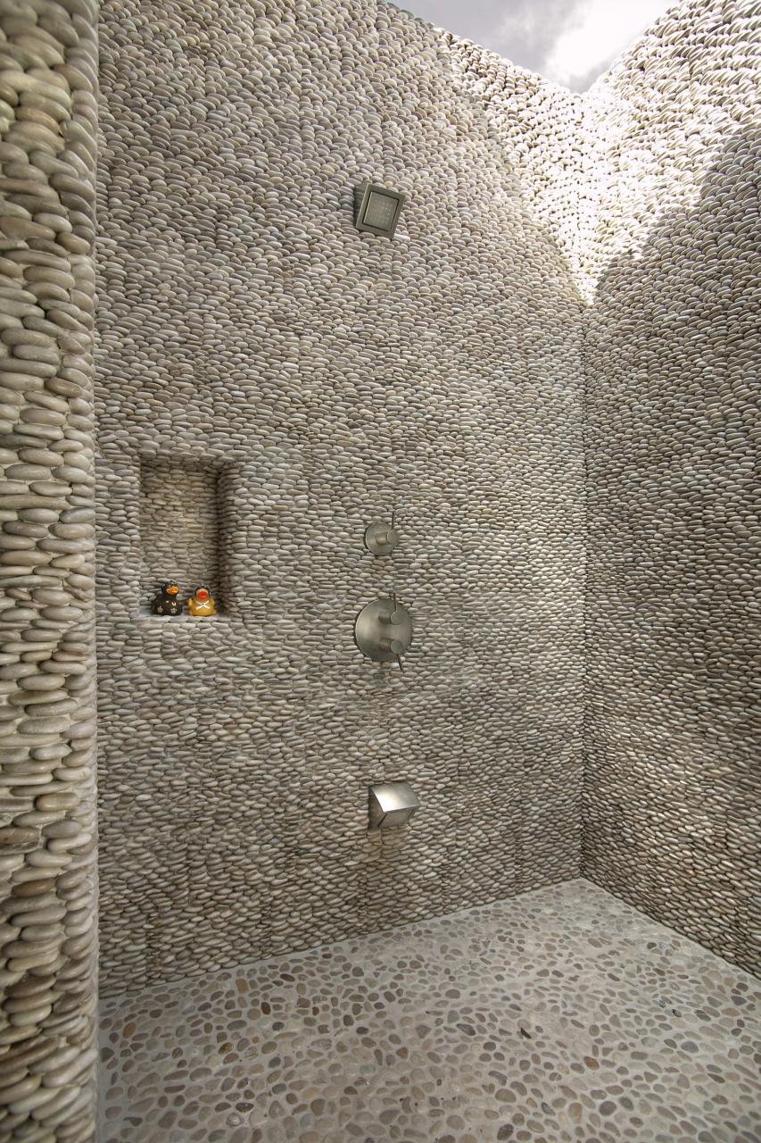 THE OUTDOOR POOL SHOWER IS OPEN TO THE SKY AND MADE FROM THOUSANDS OF INTERLOCKED PEBBLES.