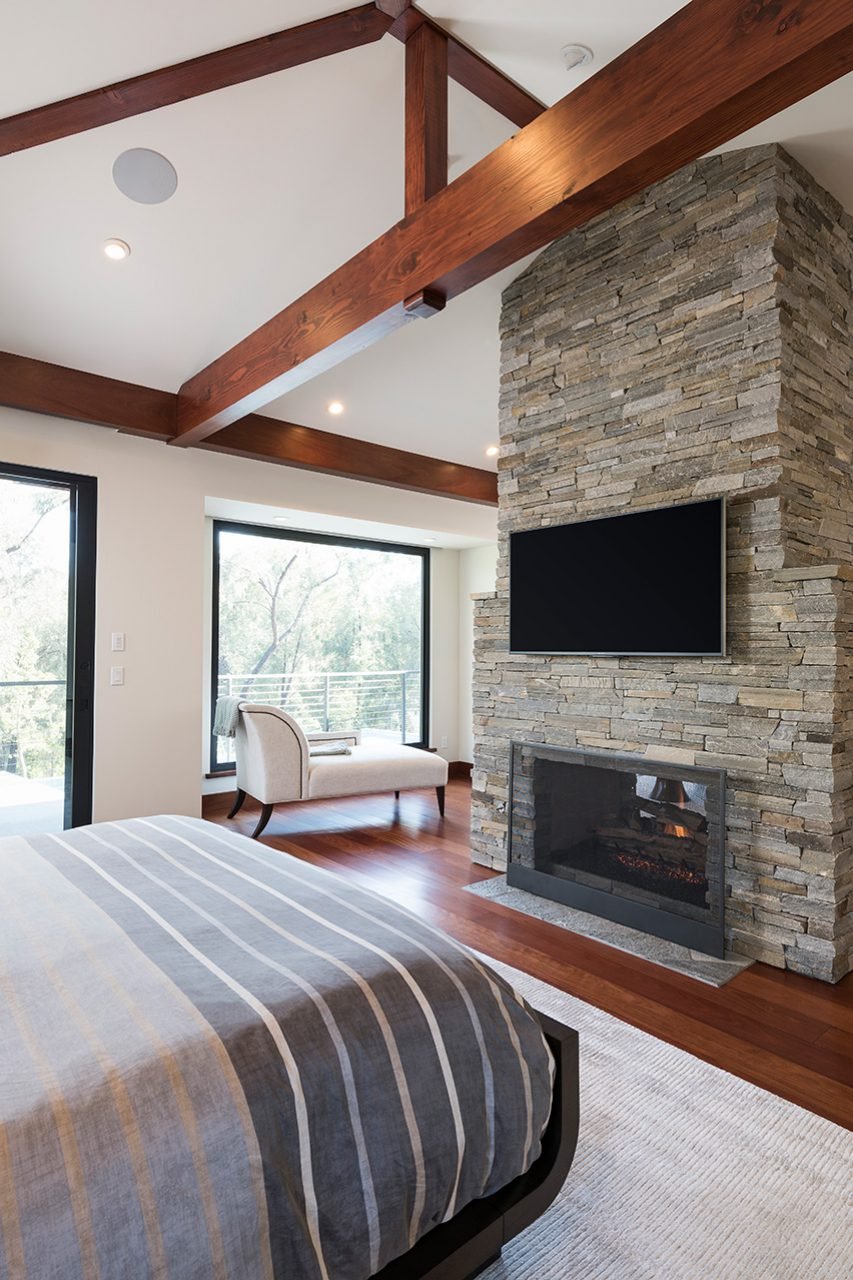 MORE EXPOSED REDWOOD BEAMS RUN THROUGH THE MASTER BEDROOM, WHICH ALSO HAS A DOUBLE-SIDED FIREPLACE.