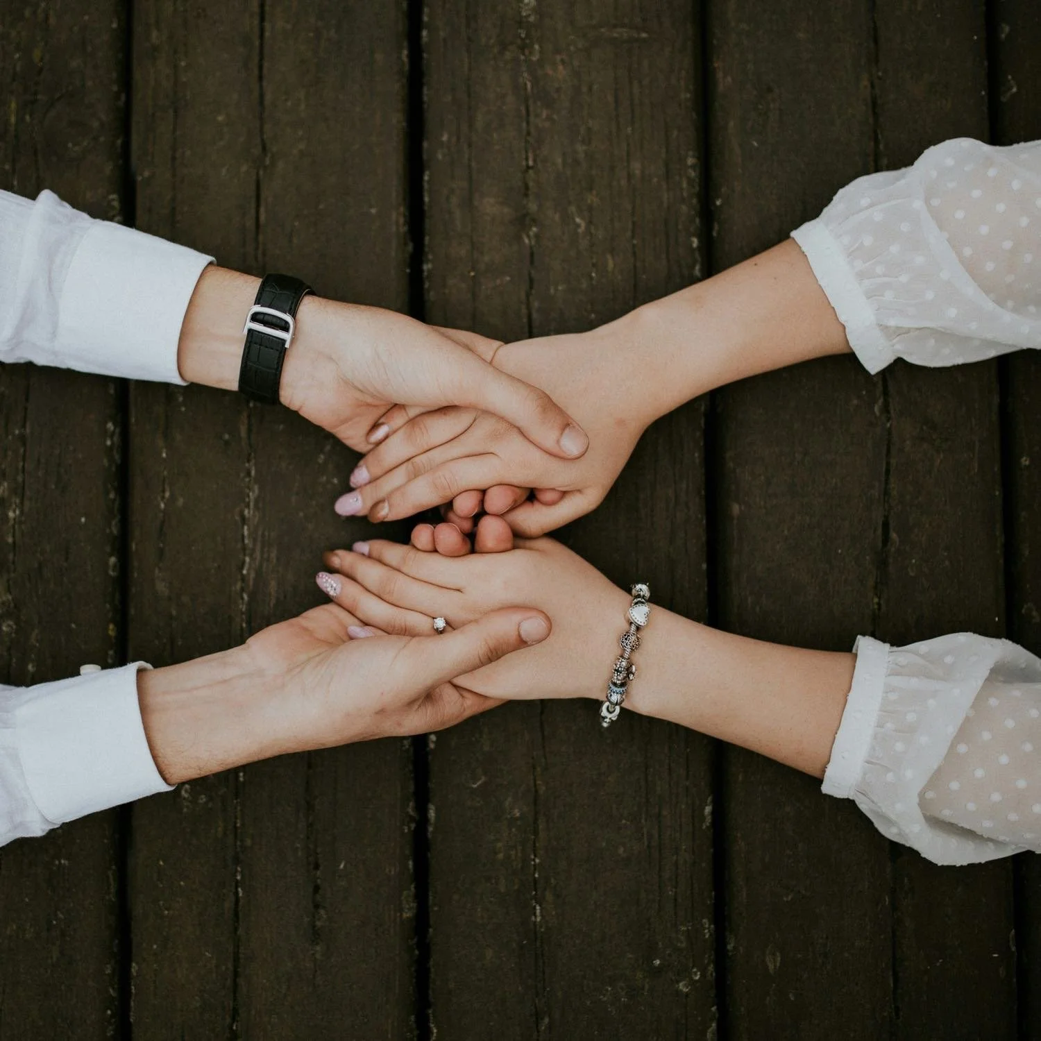 Two people holding hands in support across a table
