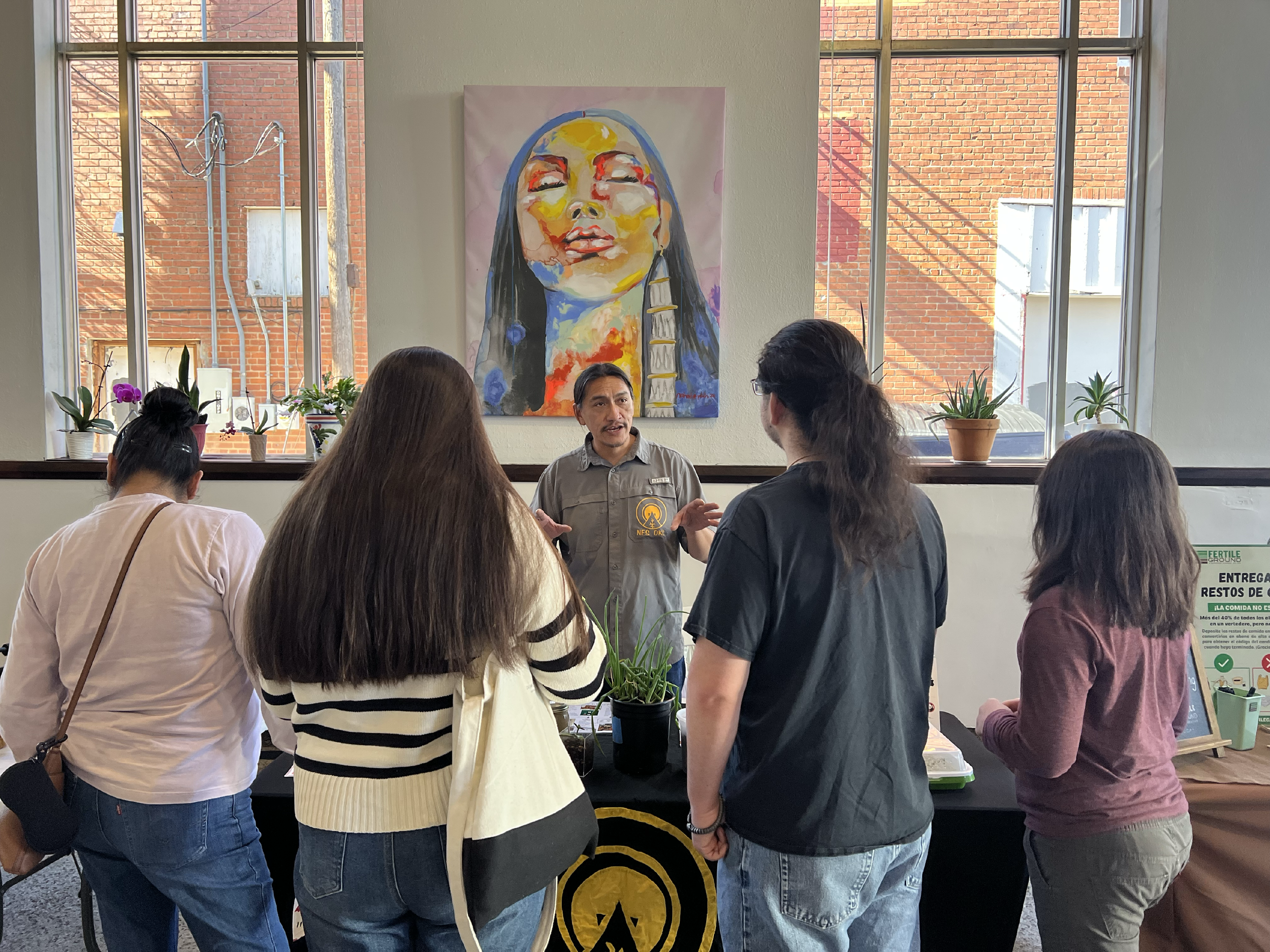 Image of Travis Andrews with Native Farming Solutions talking to a group of people who are visiting his table at Living Traditions Community Fair