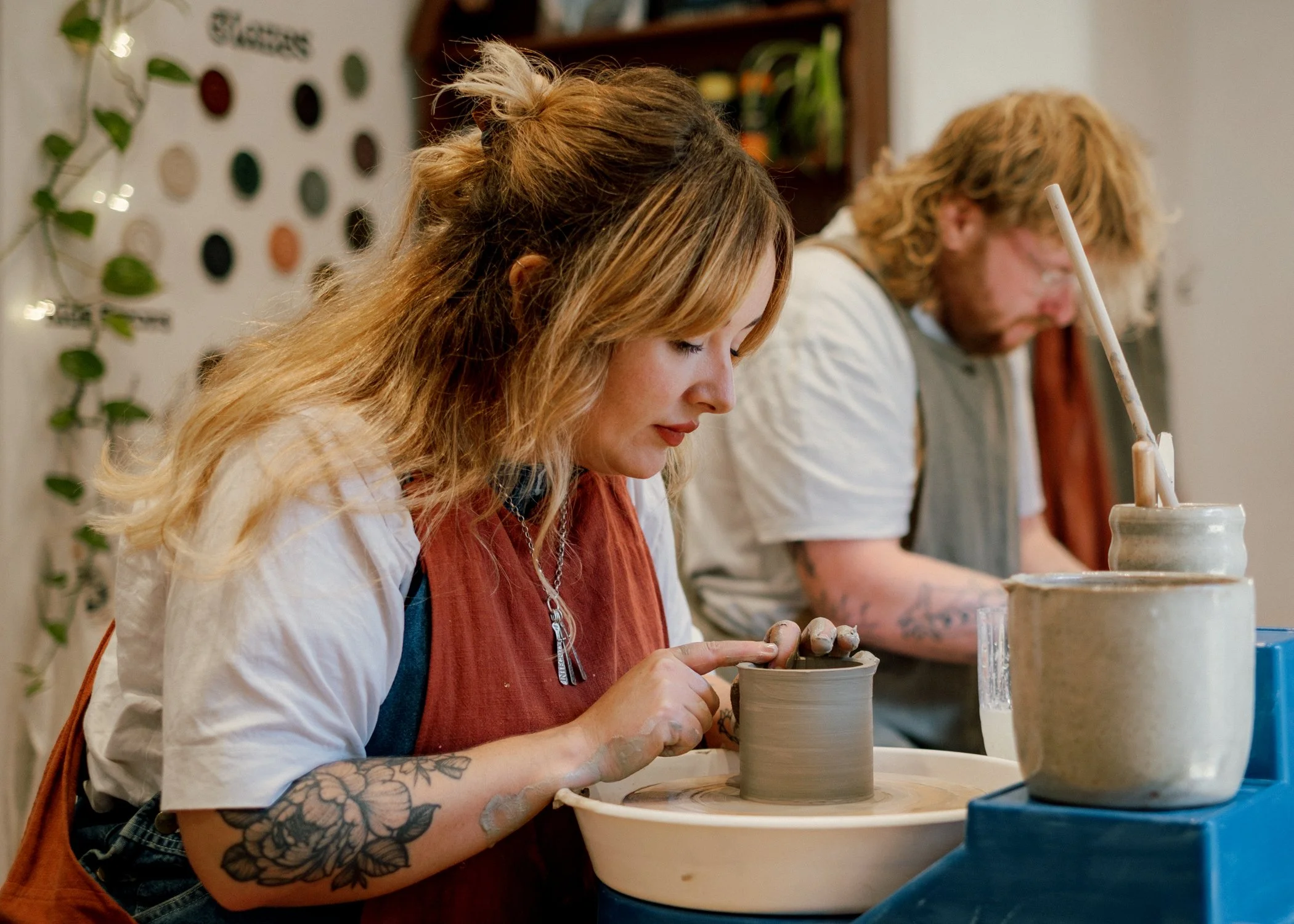 Person shaping clay on a pottery wheel with their hands covered in clay.
