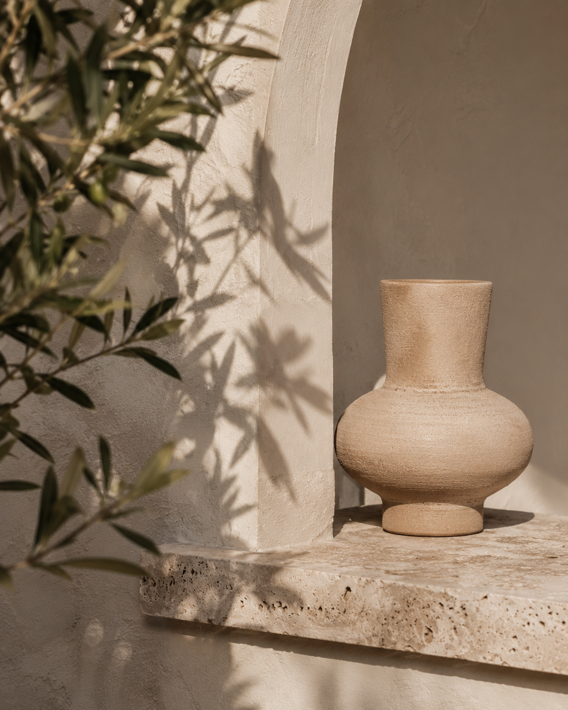 Mediterrane Wandnische mit Keramikvase, Naturstein, Olivenzweigen und sanftem Licht für Casa Lumi.