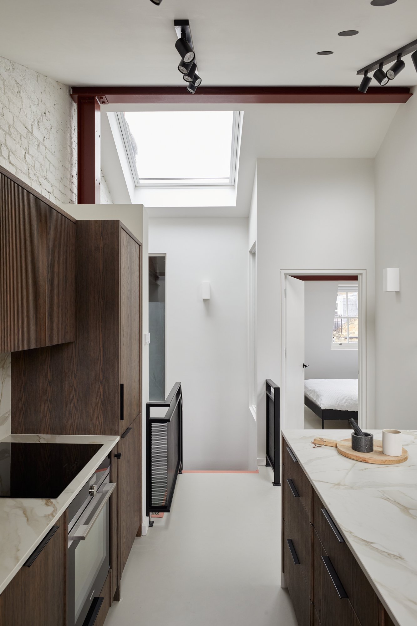 White and dark wood open plan kitchen, with marble backsplash and waterfall countertops London SW1V