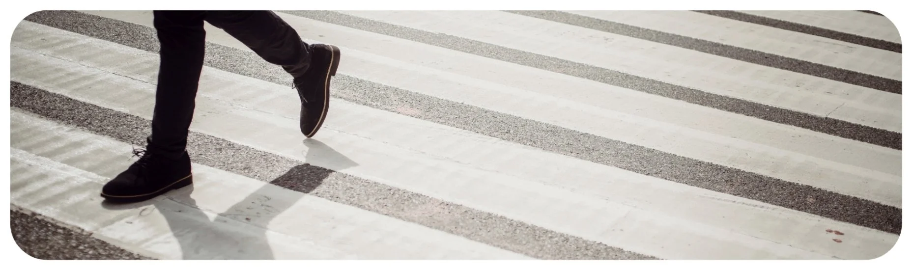 Pedestrian stepping through a marked crosswalk in Iowa, emphasizing driver awareness and pedestrian right-of-way.