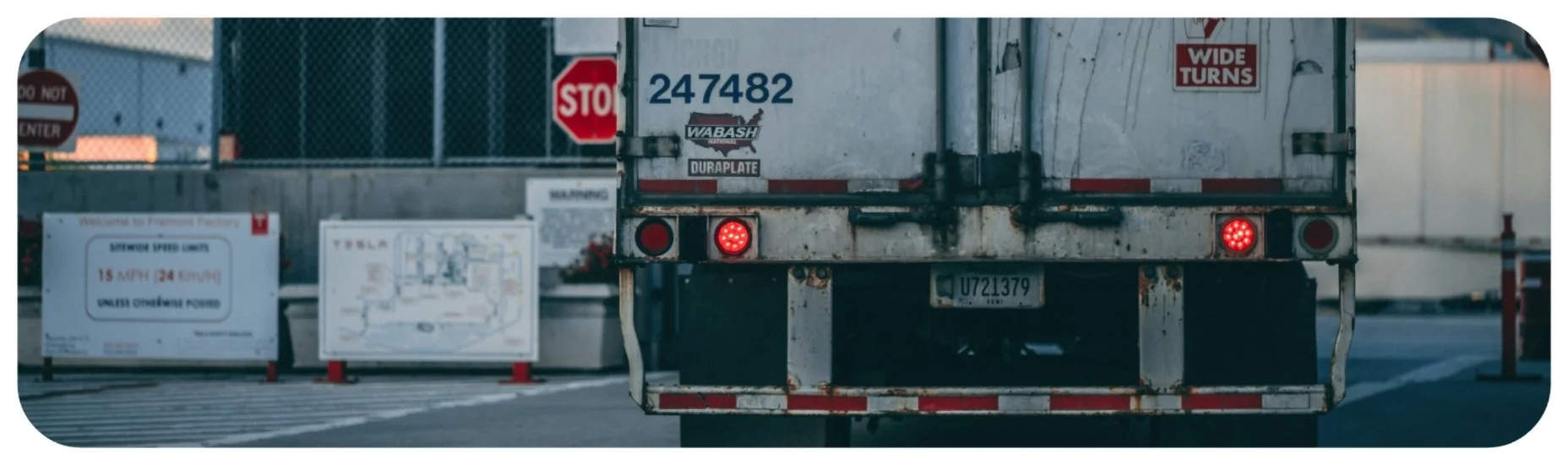 Rear view of a commercial truck displaying wide-turn warnings and brake lights, highlighting underride crash risks in Iowa.