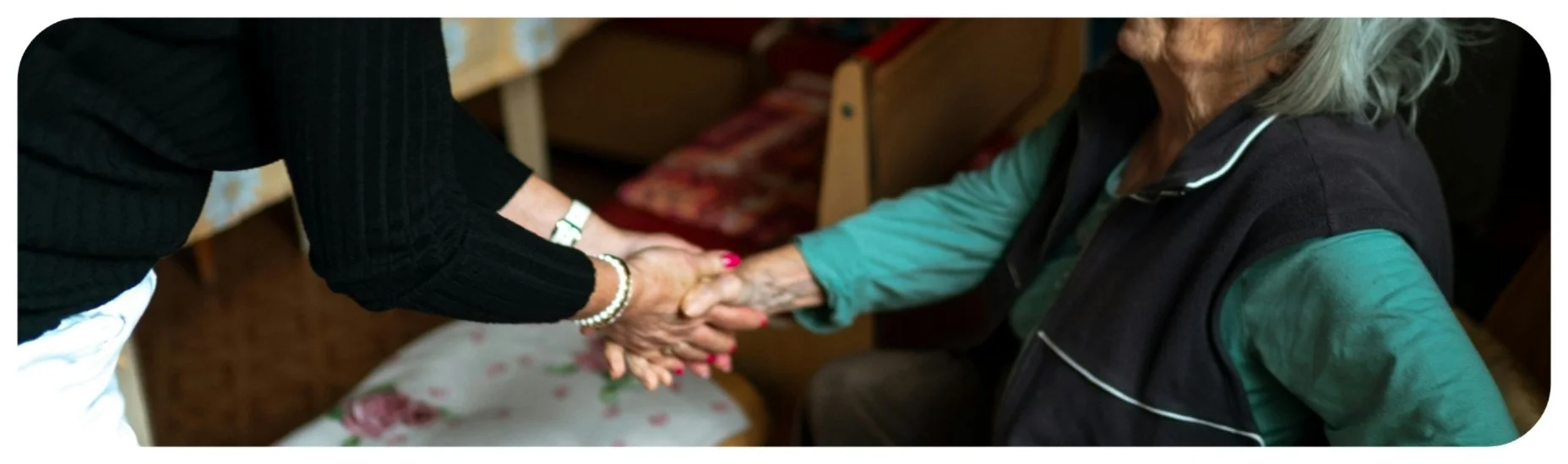 Caregiver holding elderly resident’s hand in an Iowa nursing home, highlighting concerns about elder abuse and resident safety.