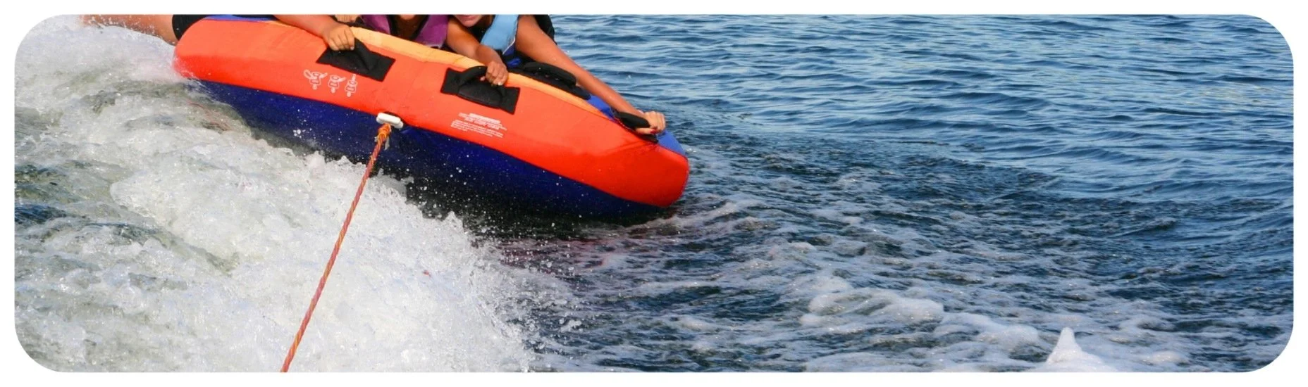 People riding an inflatable tube behind a boat, highlighting Iowa boating accidents involving towed water sports.