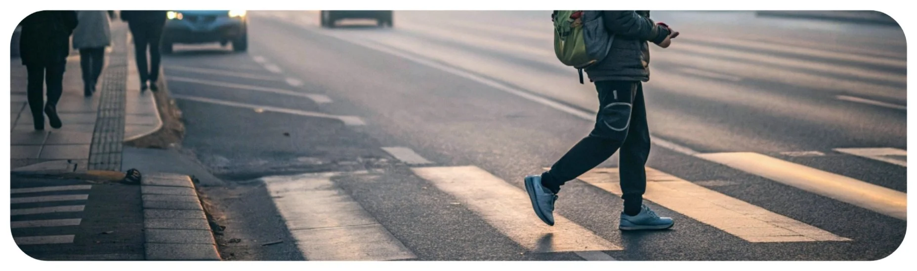 Pedestrian crossing an Iowa roadway at a marked crosswalk, illustrating the risk of vehicle-pedestrian accidents.