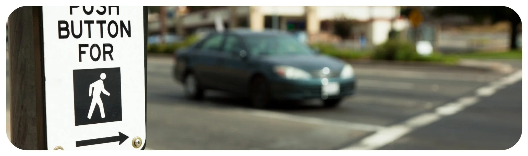 Pedestrian push-button signal at an Iowa crosswalk, highlighting driver and city responsibility for pedestrian safety.