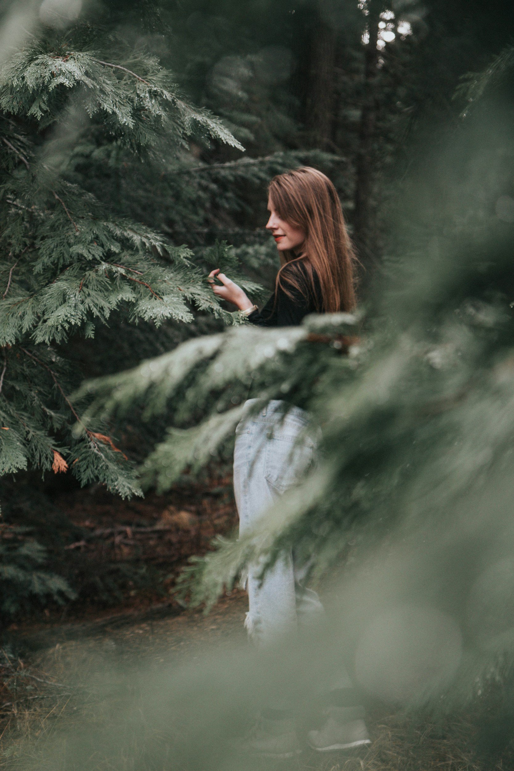 Woman in forest touching pine branches