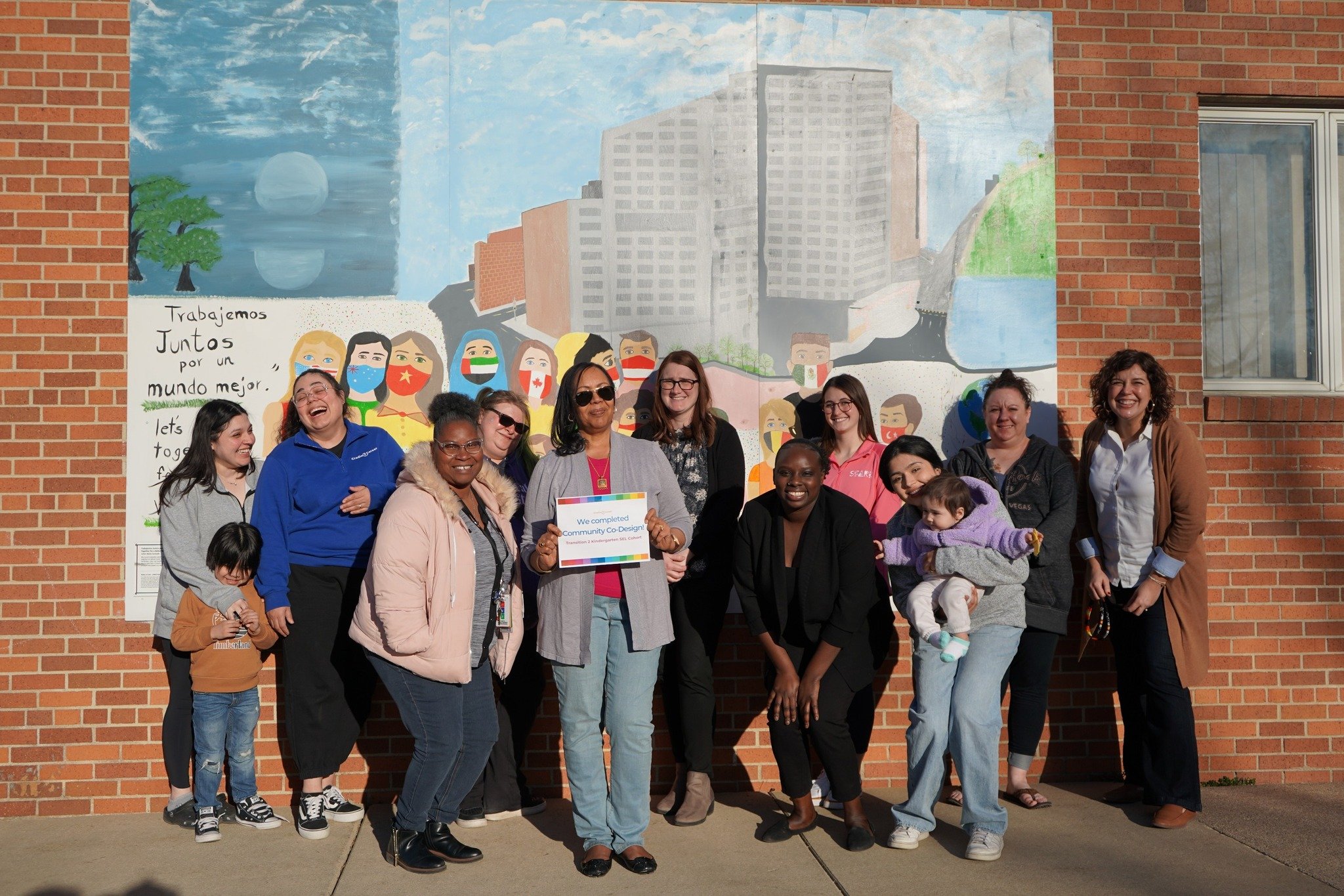 A group of people standing together smiling in front of a mural