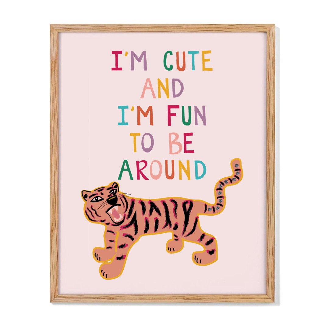 A framed art print of an original illustration by KJ of a roaring tiger with diamonds in her tail, and hand lettering that reads I'm Cute and I'm Fun to be Around.