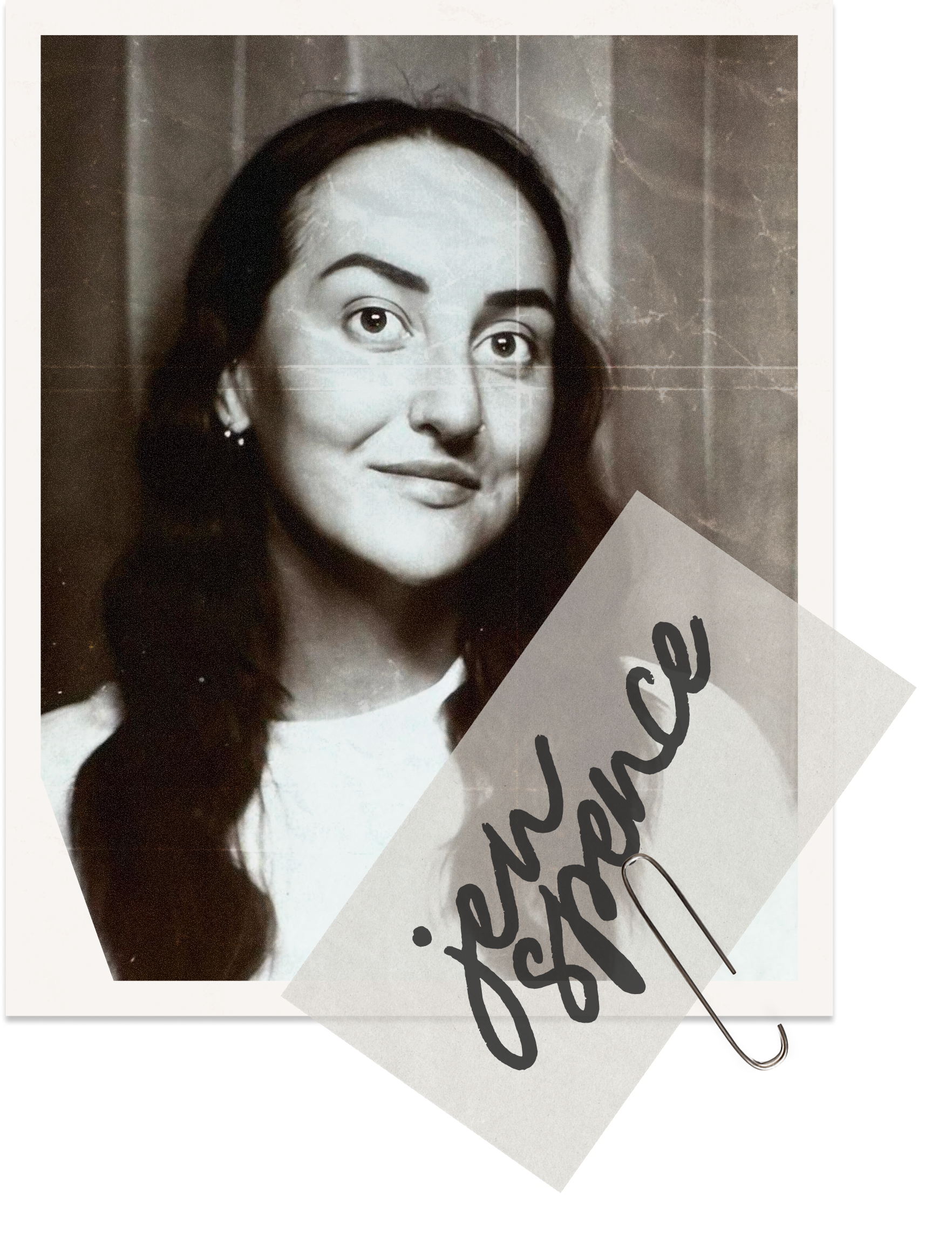 Black and white photo of a woman with long dark hair, wearing earrings, looking at the camera with a slight smile, with a sign containing handwritten text attached with a paperclip.
