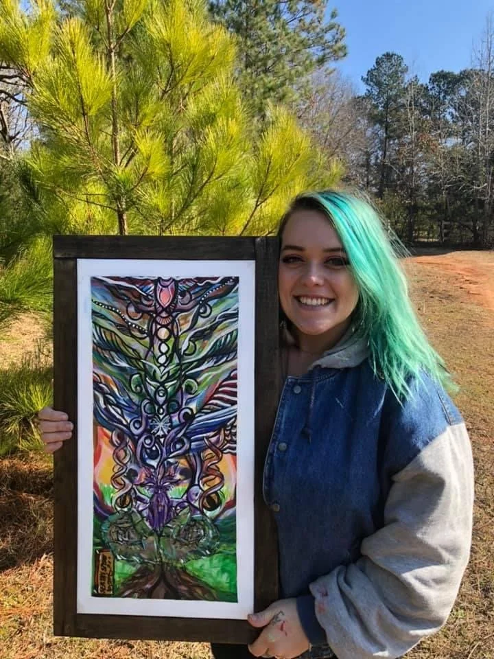 Courtnie May holding a framed Sea The Spirit original artwork