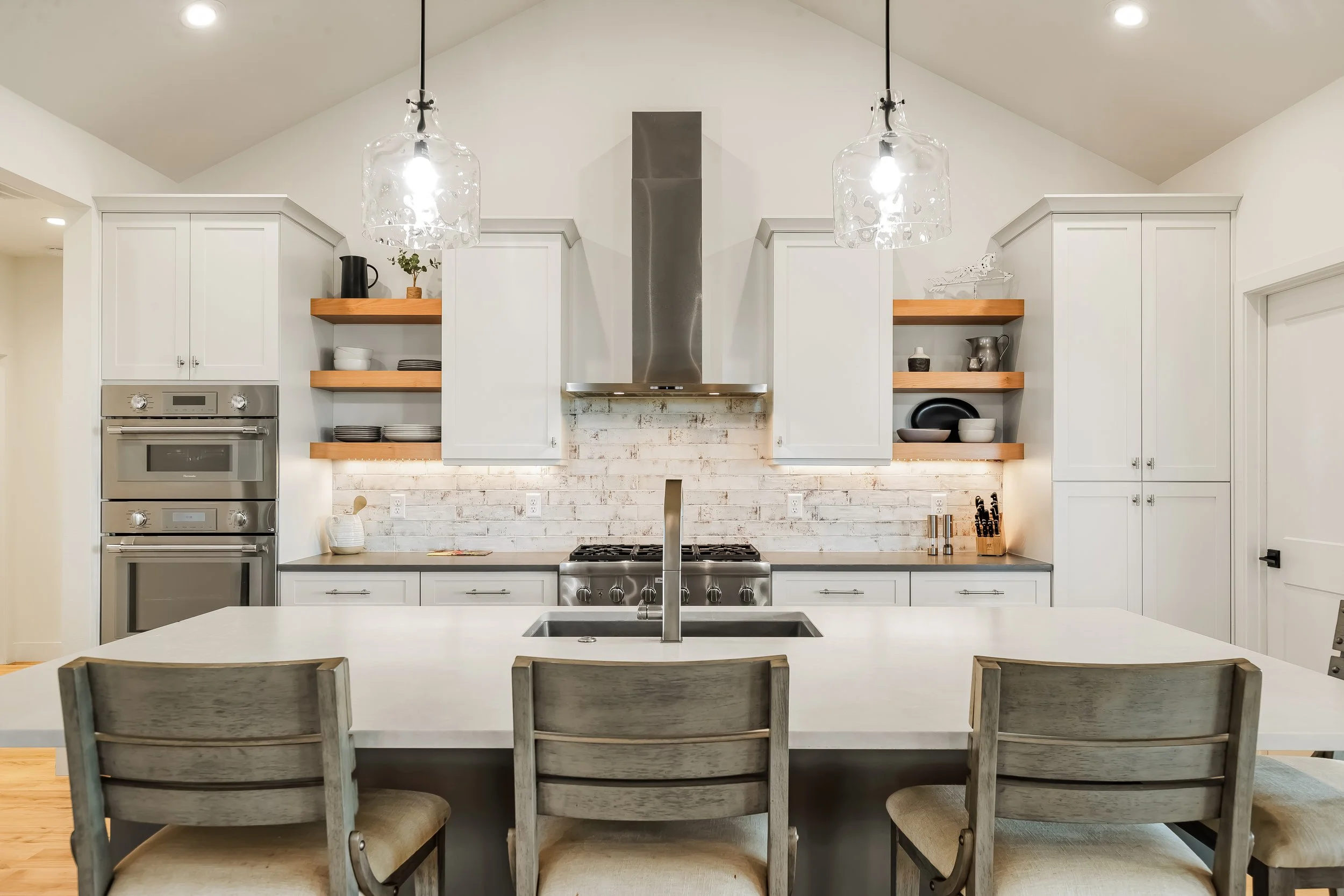 Kitchen with quartz counters, double ovens and propane range