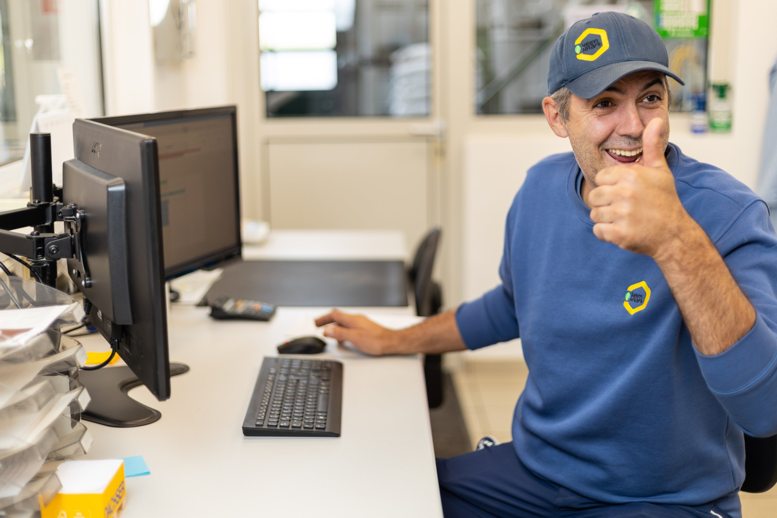 motivierter Mitarbeiter am Schreibtisch vor PC mit Daumen hoch