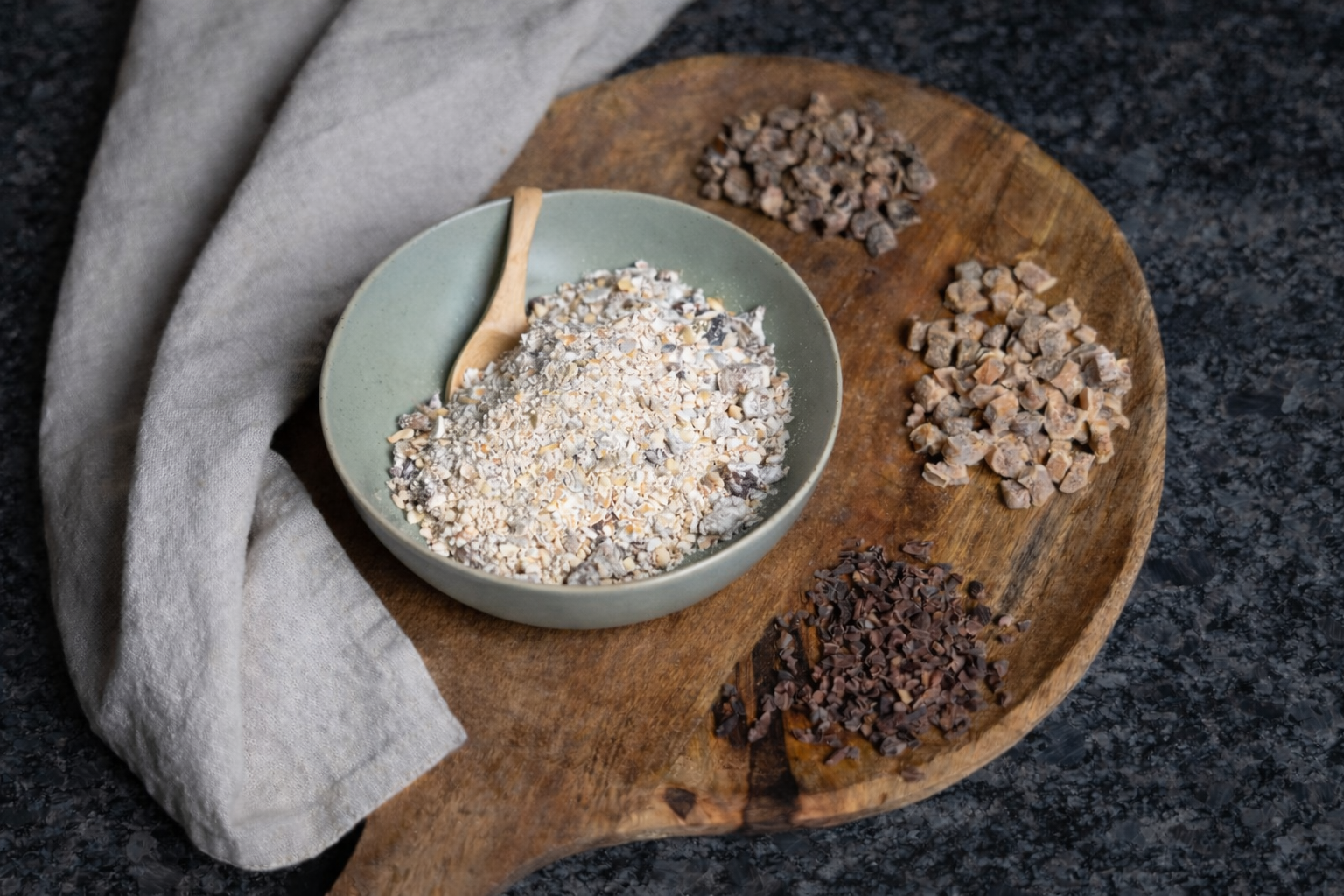 Schüssel mit Müslimischung und Löffel auf einem Holzuntergrund auf denen auch getrocknete Früchte trappiert sind ;mit Serviette