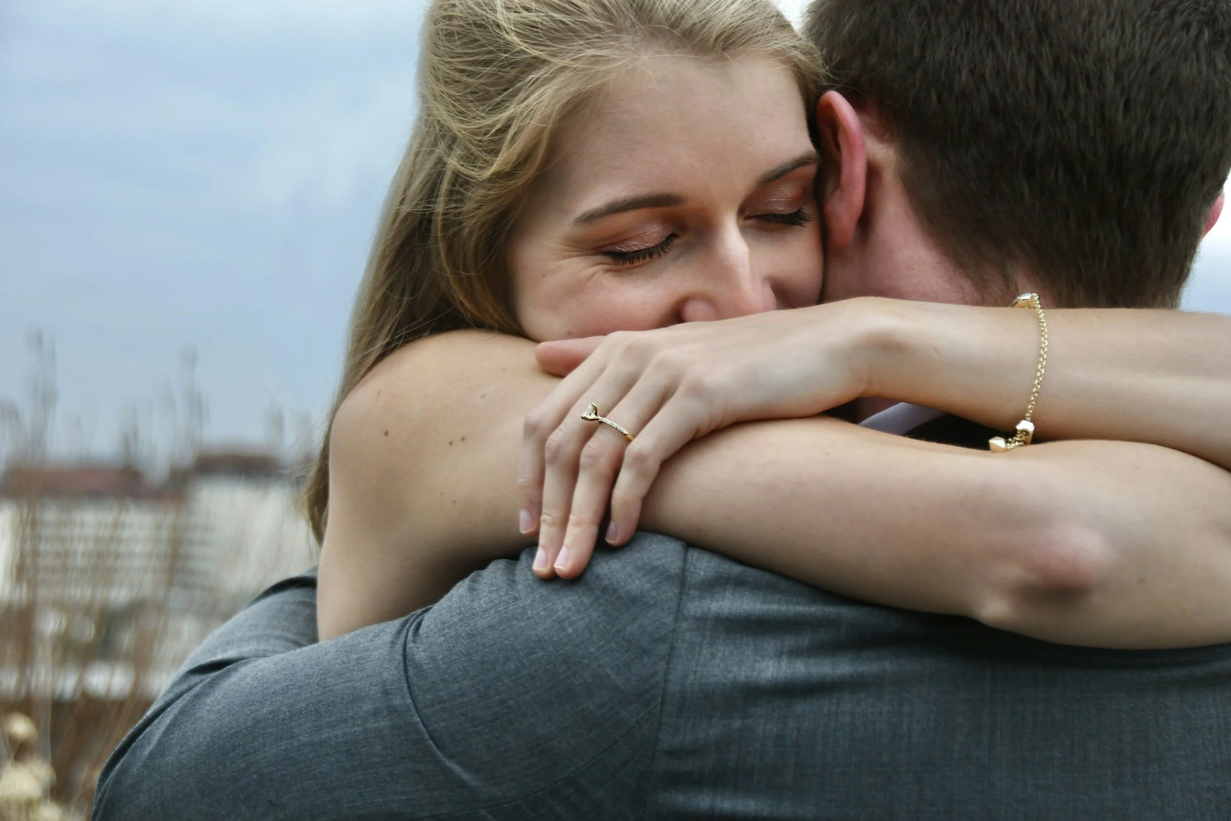 A woman and a man embracing outdoors, with the woman’s face visible and eyes closed, showing affection and comfort. They may benefit from a from therapy provided by Empowering Hope and our skilled therapists.
