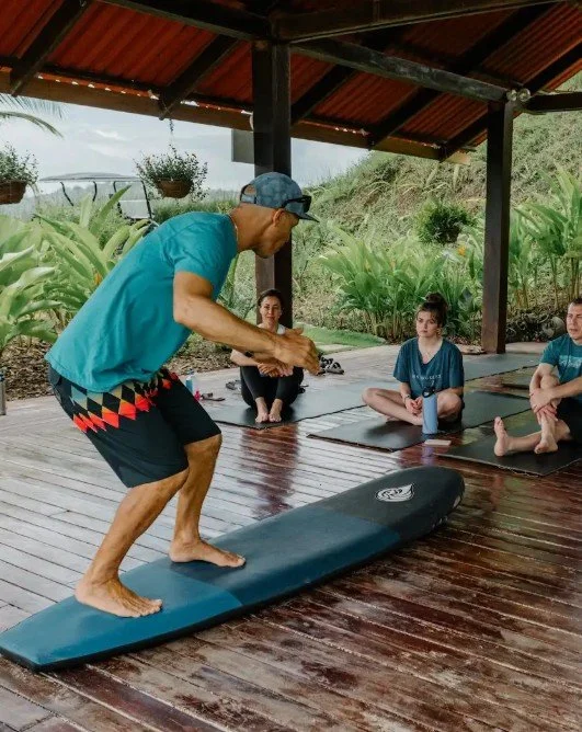 Surf instructor demonstrating proper surfboard technique on land.