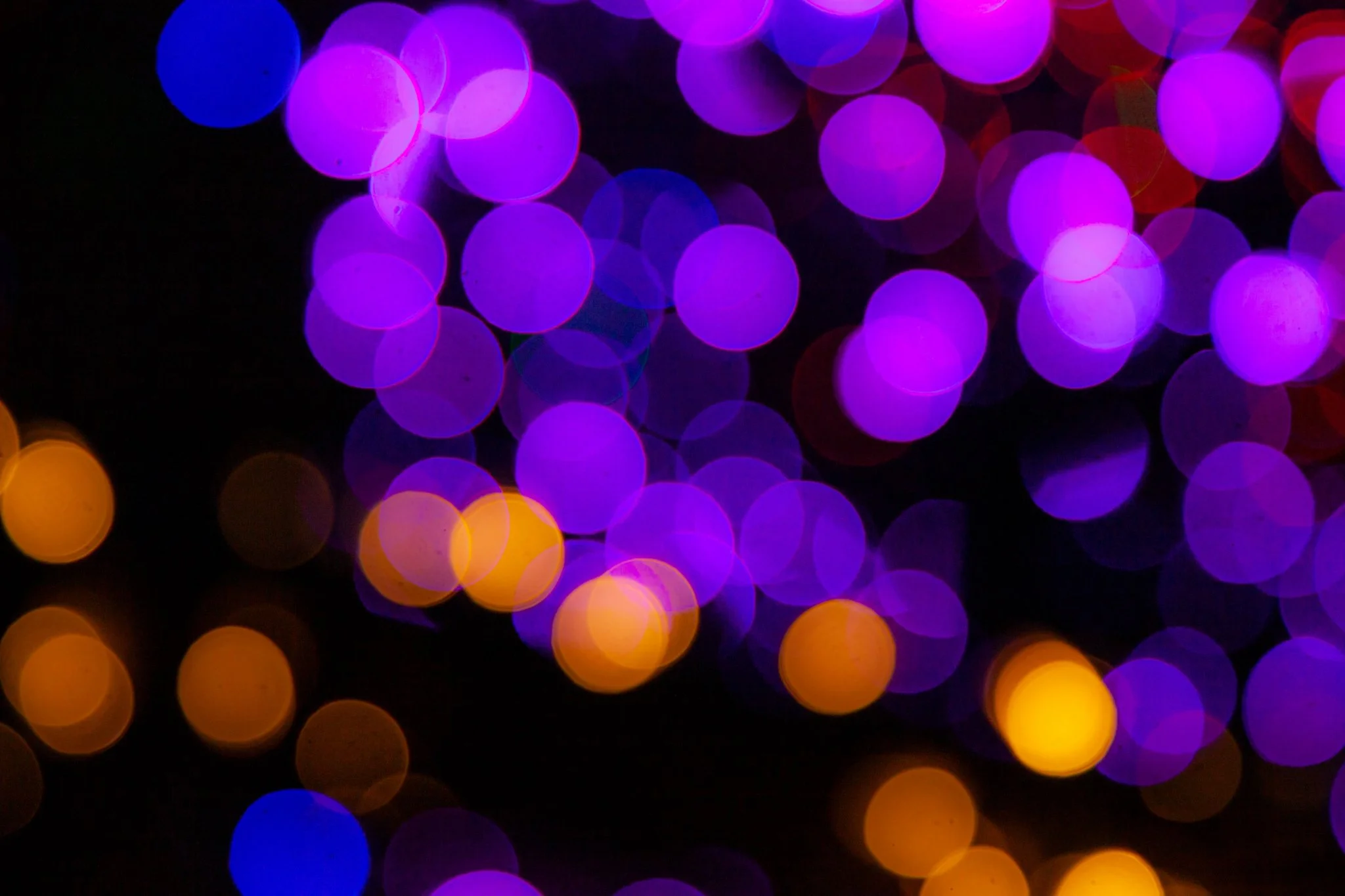 Blurry colorful lights in purple, yellow, red, and blue hues creating a bokeh effect.