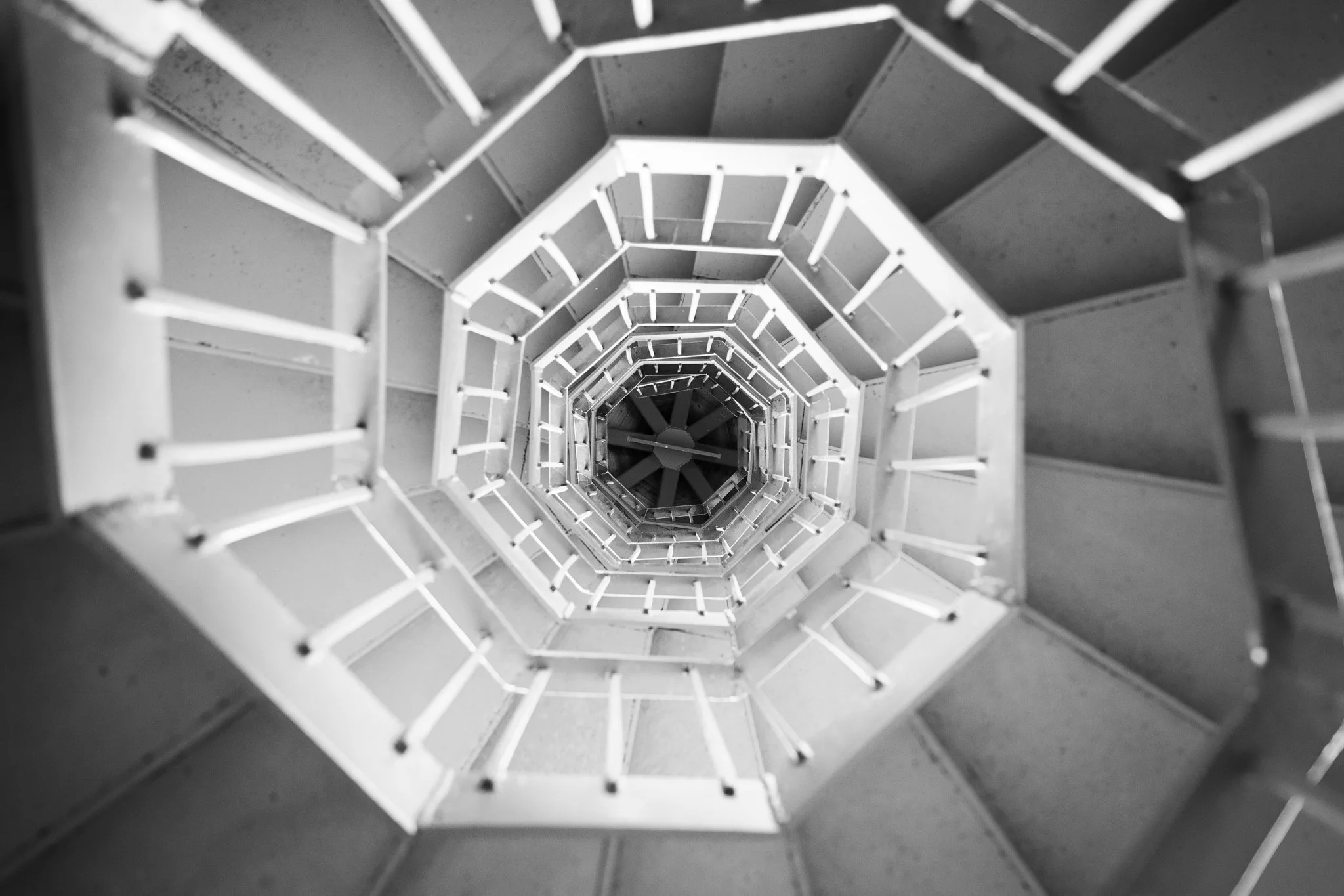 A black-and-white view looking down the center of a spiral staircase.