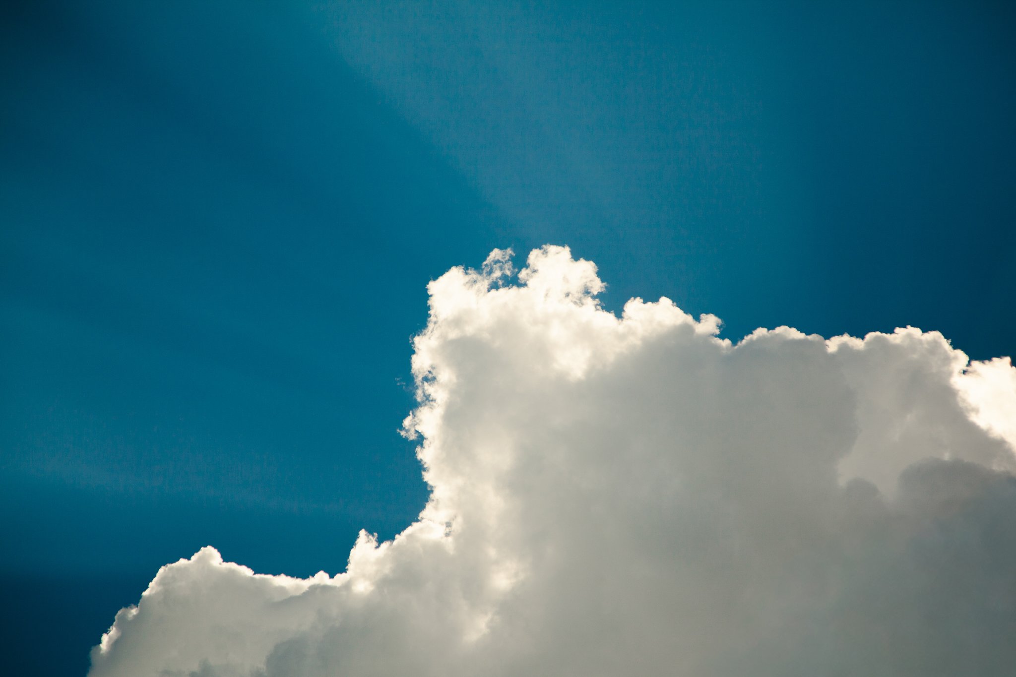 Partly cloudy sky with white clouds and blue background.
