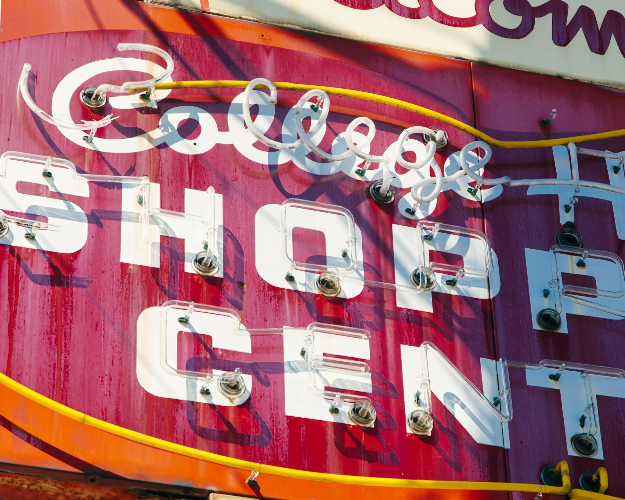 Close-up of a vintage sign with neon lights, partially showing the word 'Soda' on a red background, with colorful wiring and bulbs.