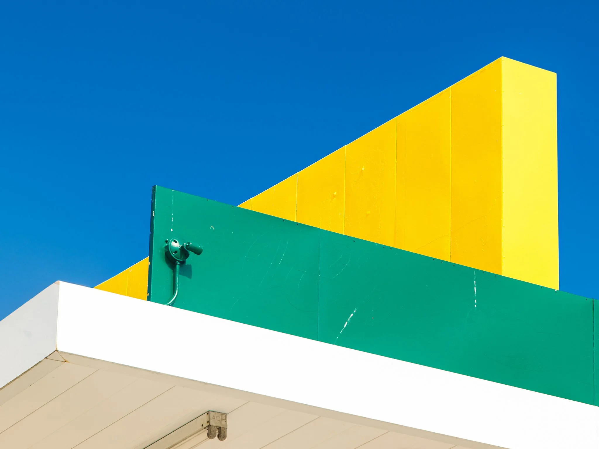 Colorful storefront with large yellow and green panels against a blue sky.