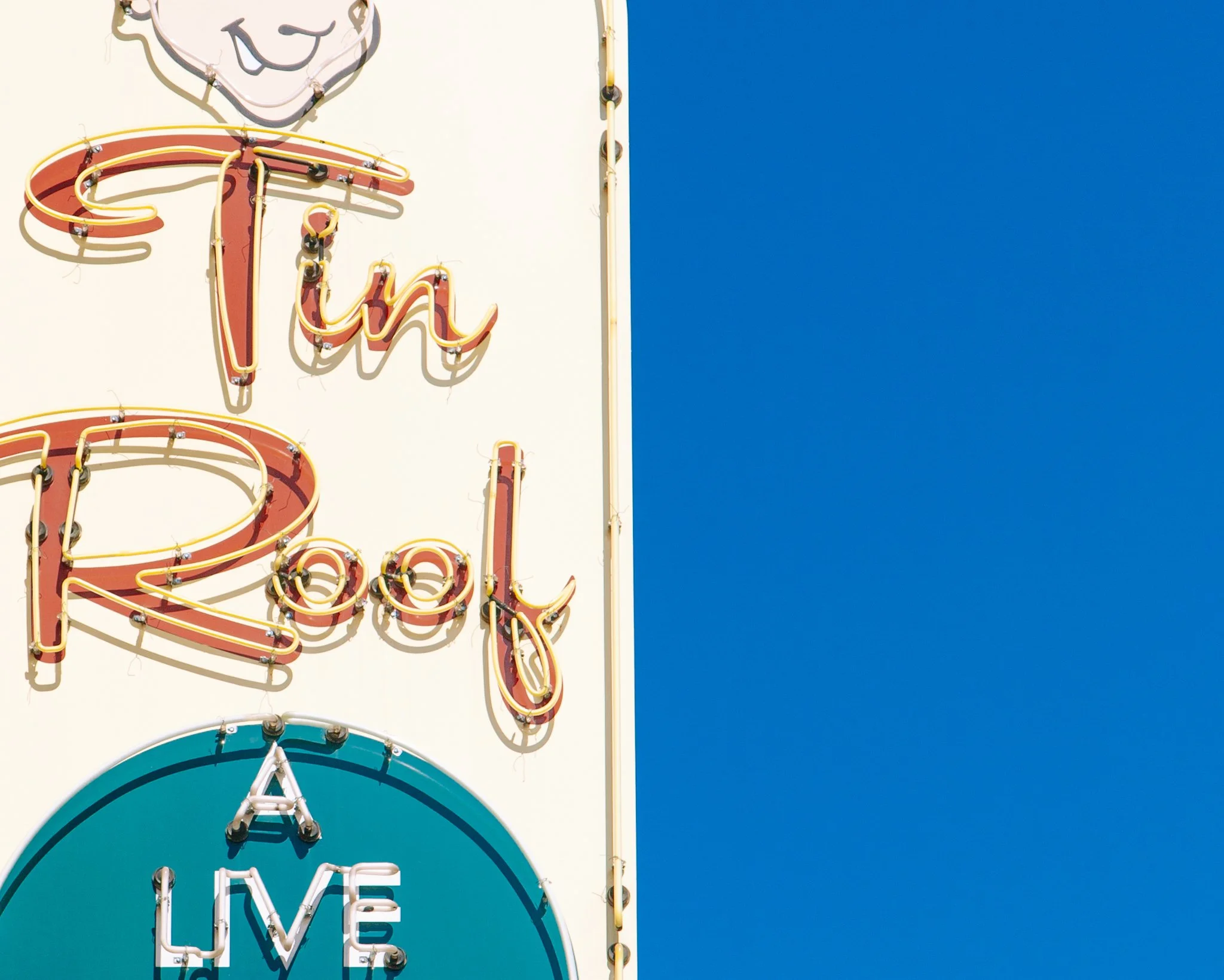 Close-up of a vintage neon sign with the words 'Turn' and 'Love' against a bright blue sky.