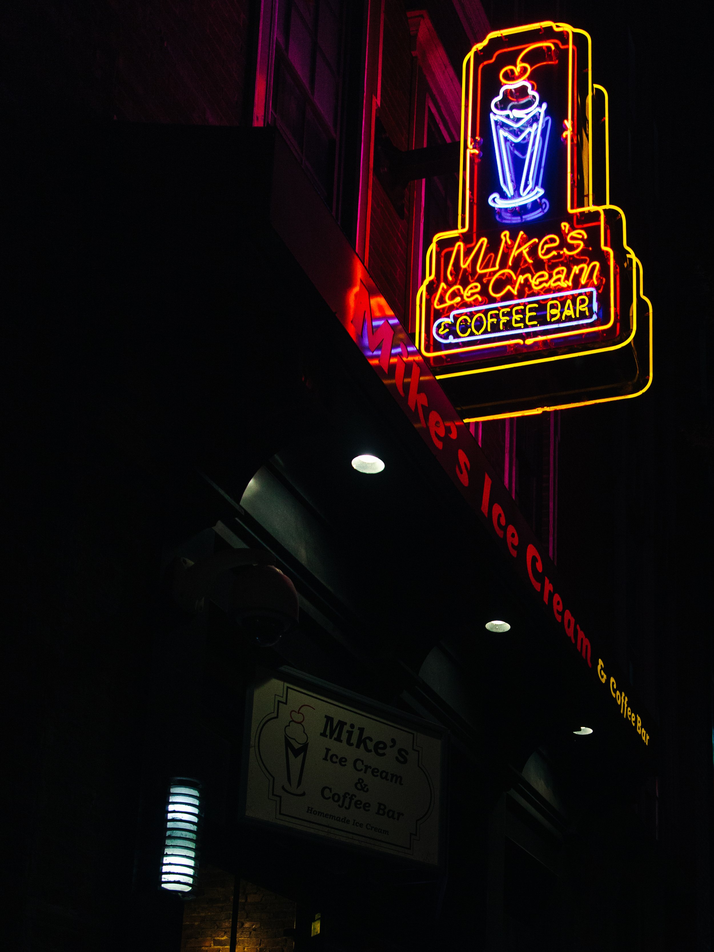 Neon sign for Mike's Ice Cream & Coffee Bar at night, with a depiction of an ice cream cone and colorful neon lights.