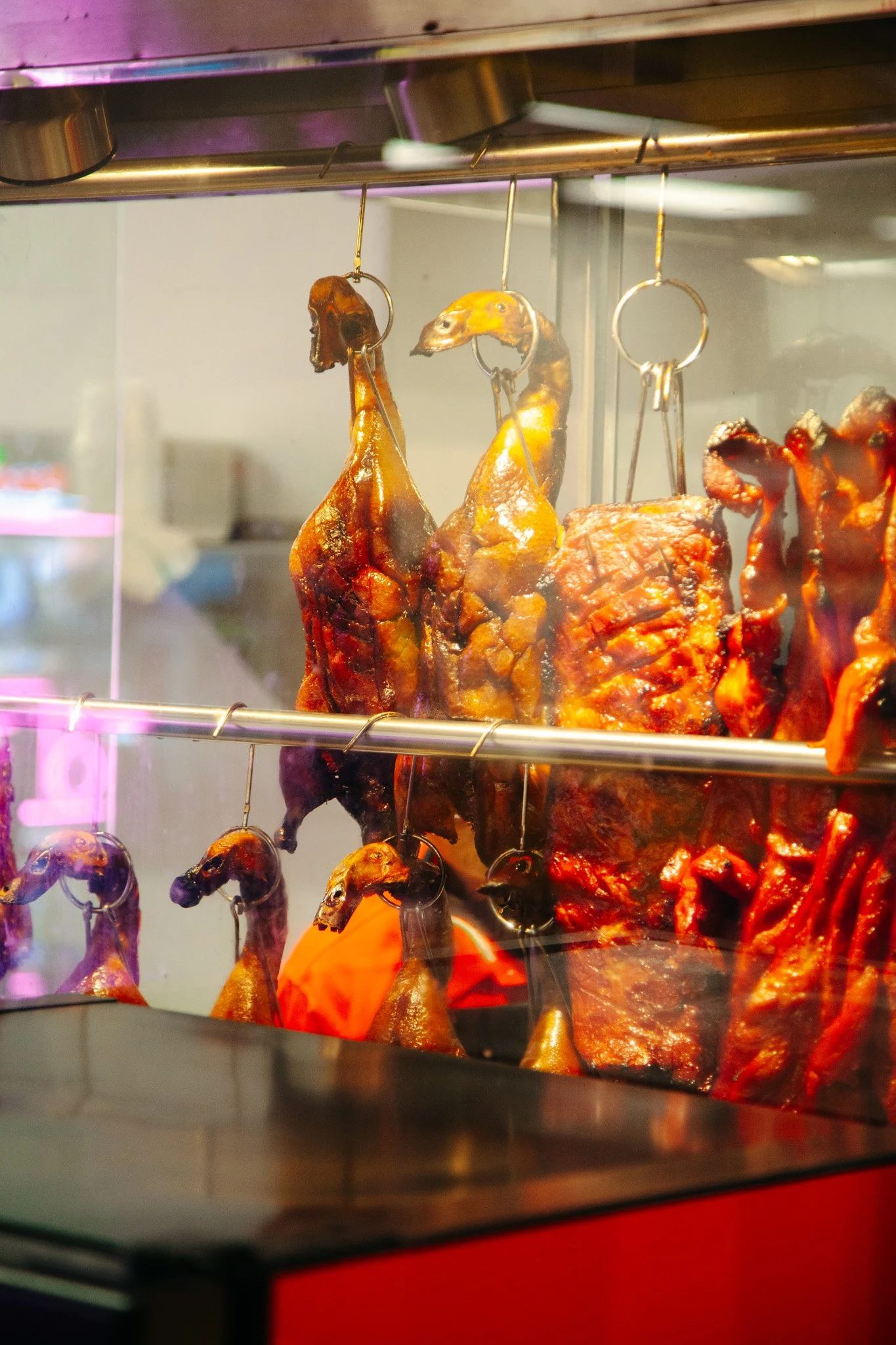 Assorted roasted meats hanging behind a glass display case at Pan-Asia Supermarket in Antioch, TN