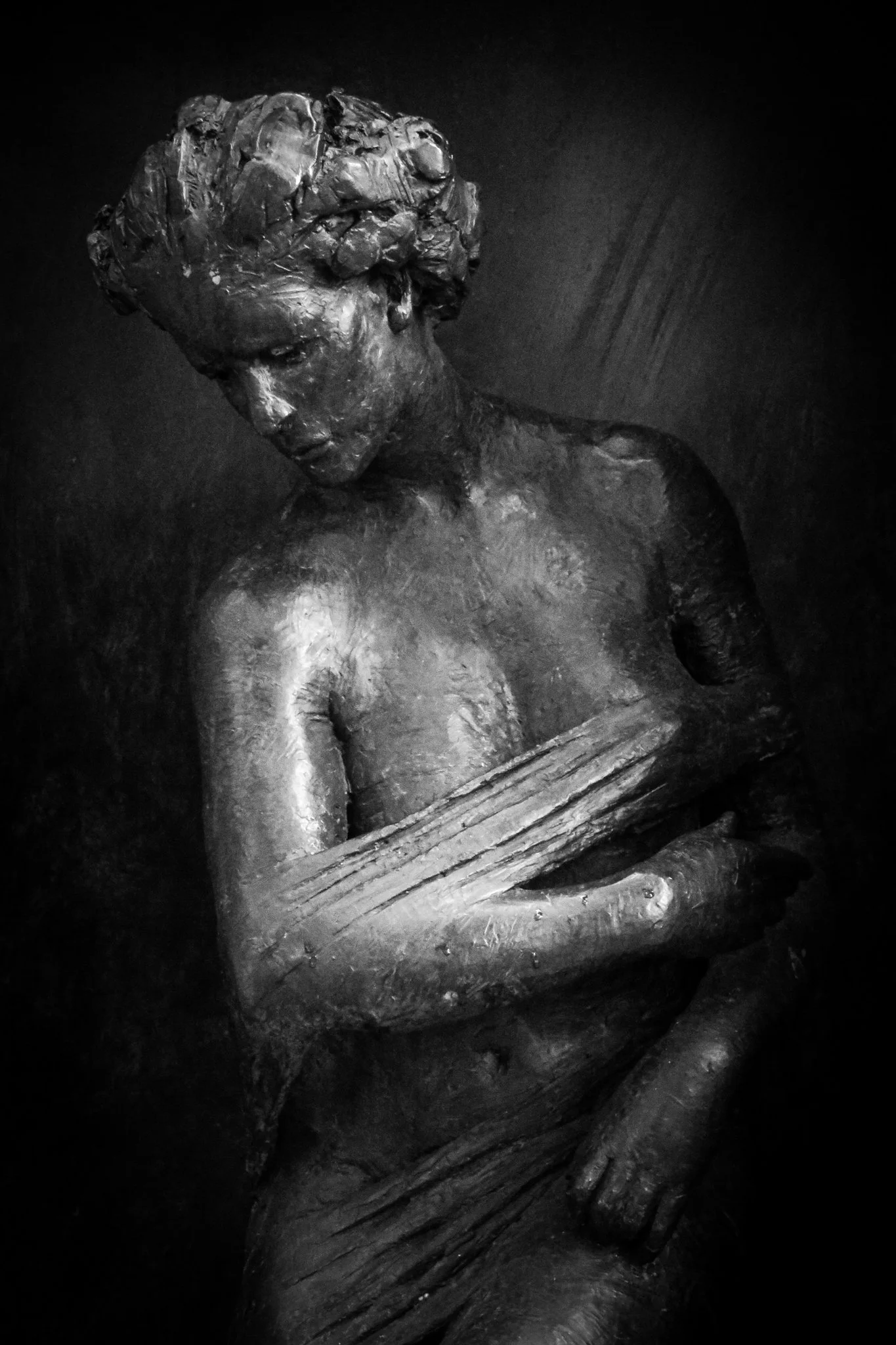 A detailed black and white sculpture of a woman holding a whale, with textured surfaces and expressive features.