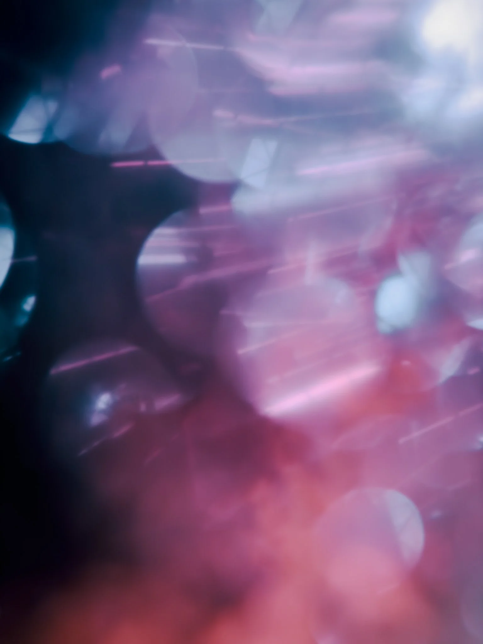 Blurred abstract background with pink, purple, and blue light streaks and bokeh effects.