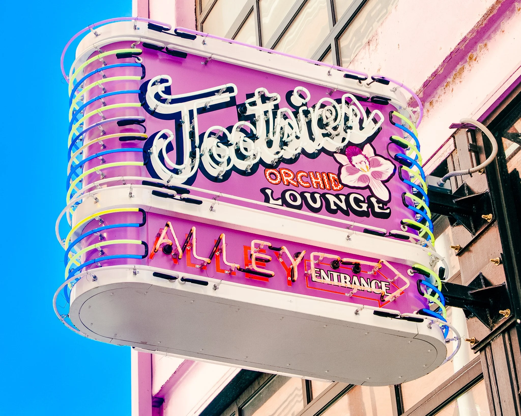Neon sign for 'The Orchid Lounge' with colorful lights and floral decoration, possibly part of a building facade.