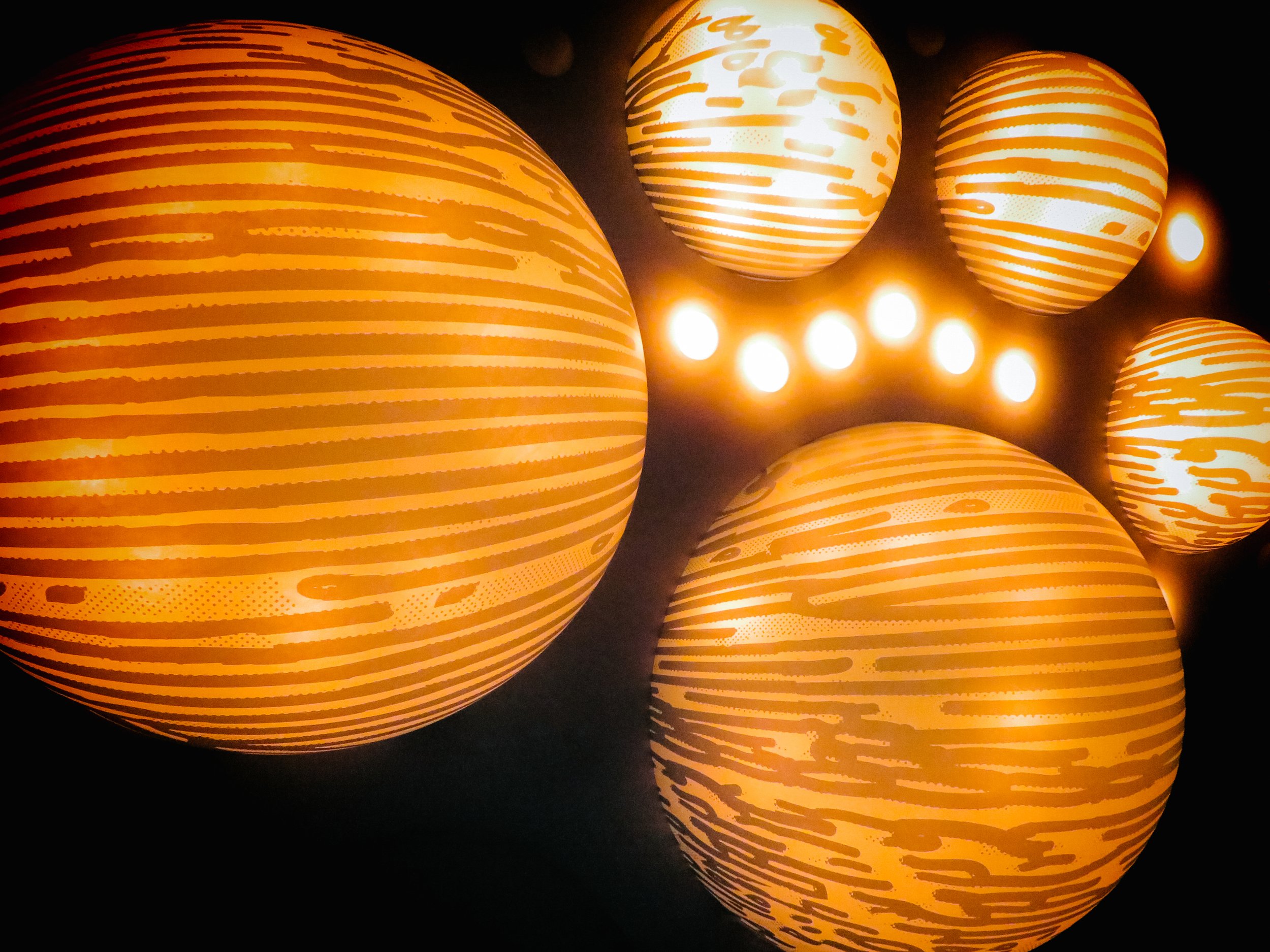 Multiple orange lanterns with swirling stripe patterns glowing against a dark background.