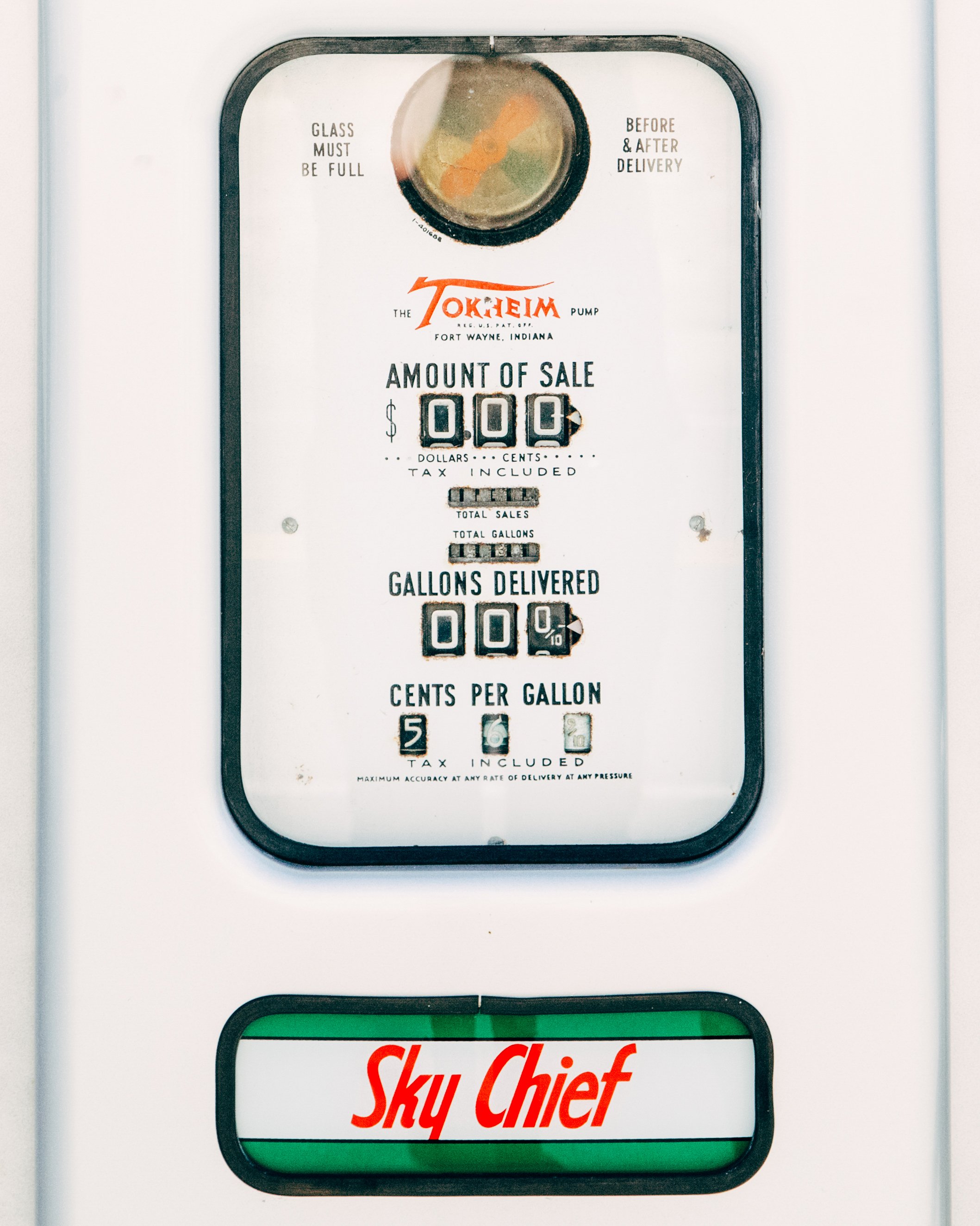 Vintage gas pump with a metal faceplate displaying sale amounts and gallons, and a sign with the Sky Chief logo.