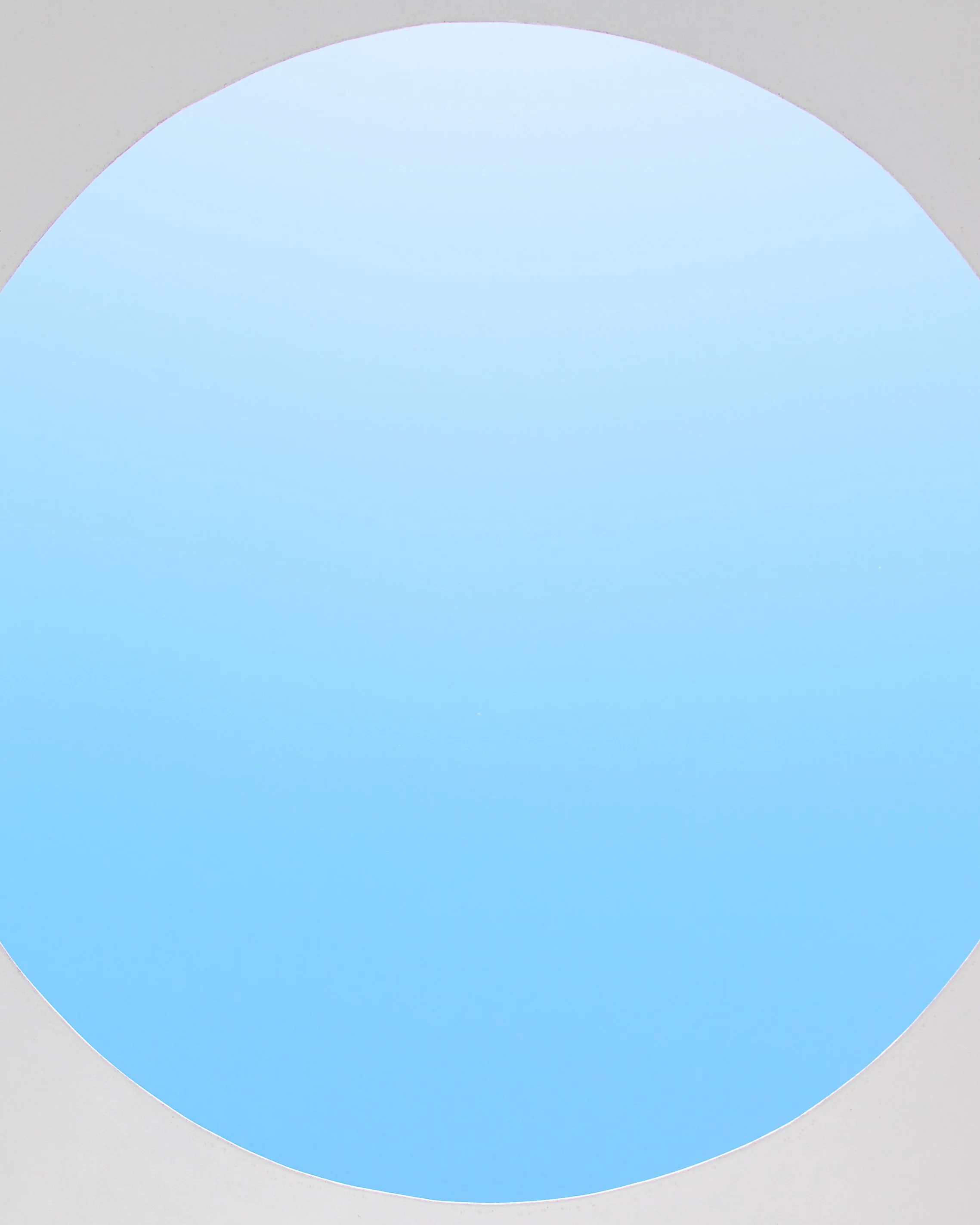 A view through an oval-shaped window showing a pale blue sky.
