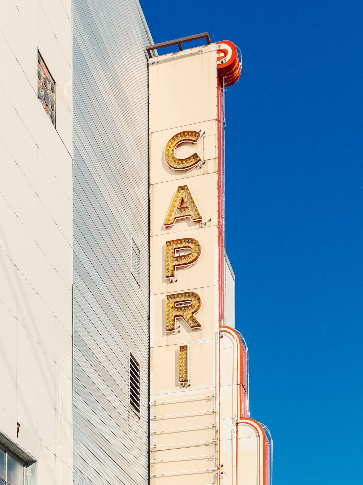A vertical shot of a building with a vintage sign that spells 'CARTER' in large illuminated letters against a bright blue sky.