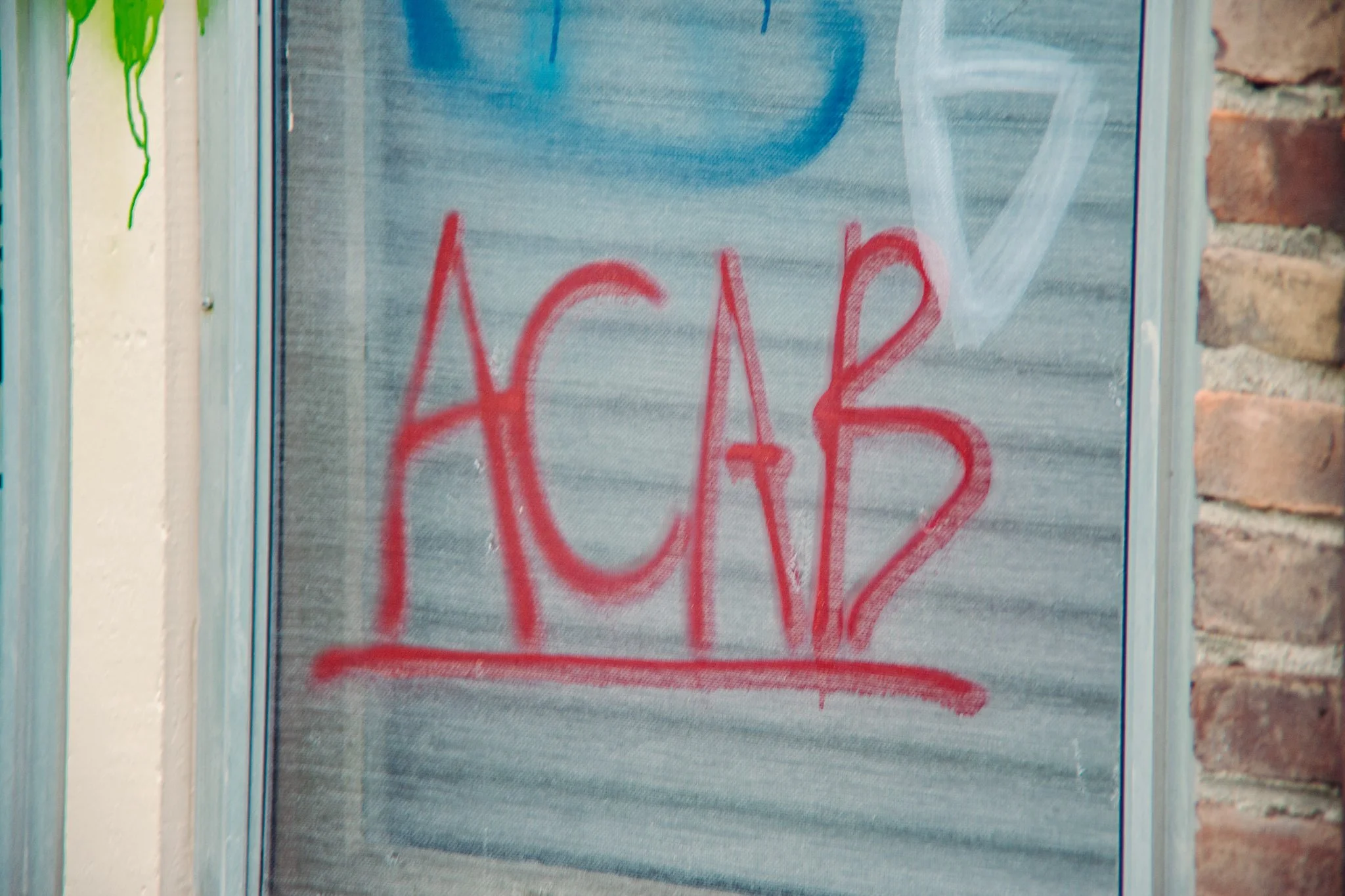 A window with graffiti painted on its screen. The graffiti includes a red word starting with 'H' near the bottom part of the window.