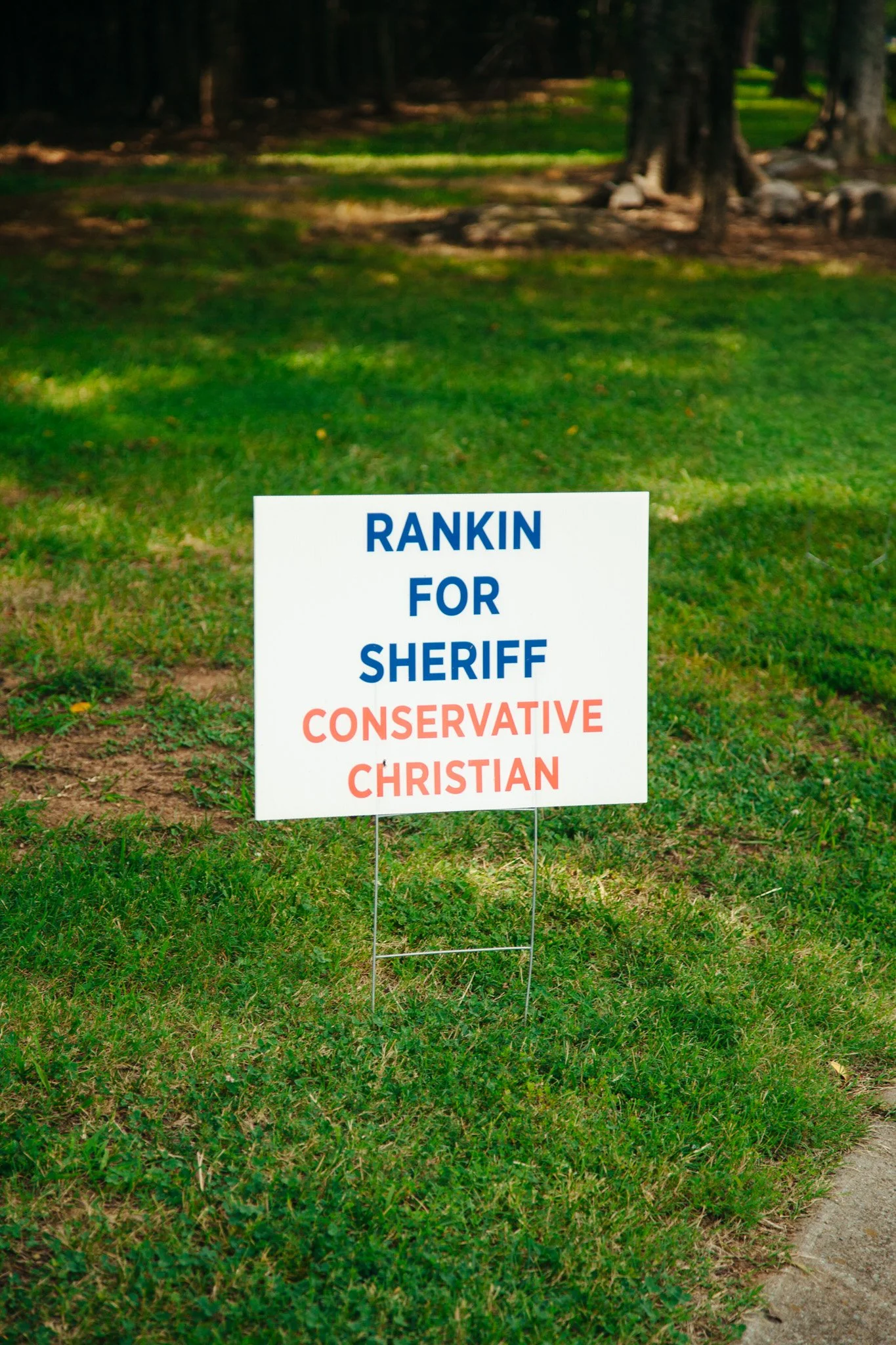 A yard sign on the grass that reads 'RANKIN FOR SHERIFF' with additional smaller text beneath that reads 'CONSERVATIVE CHRISTIAN.'