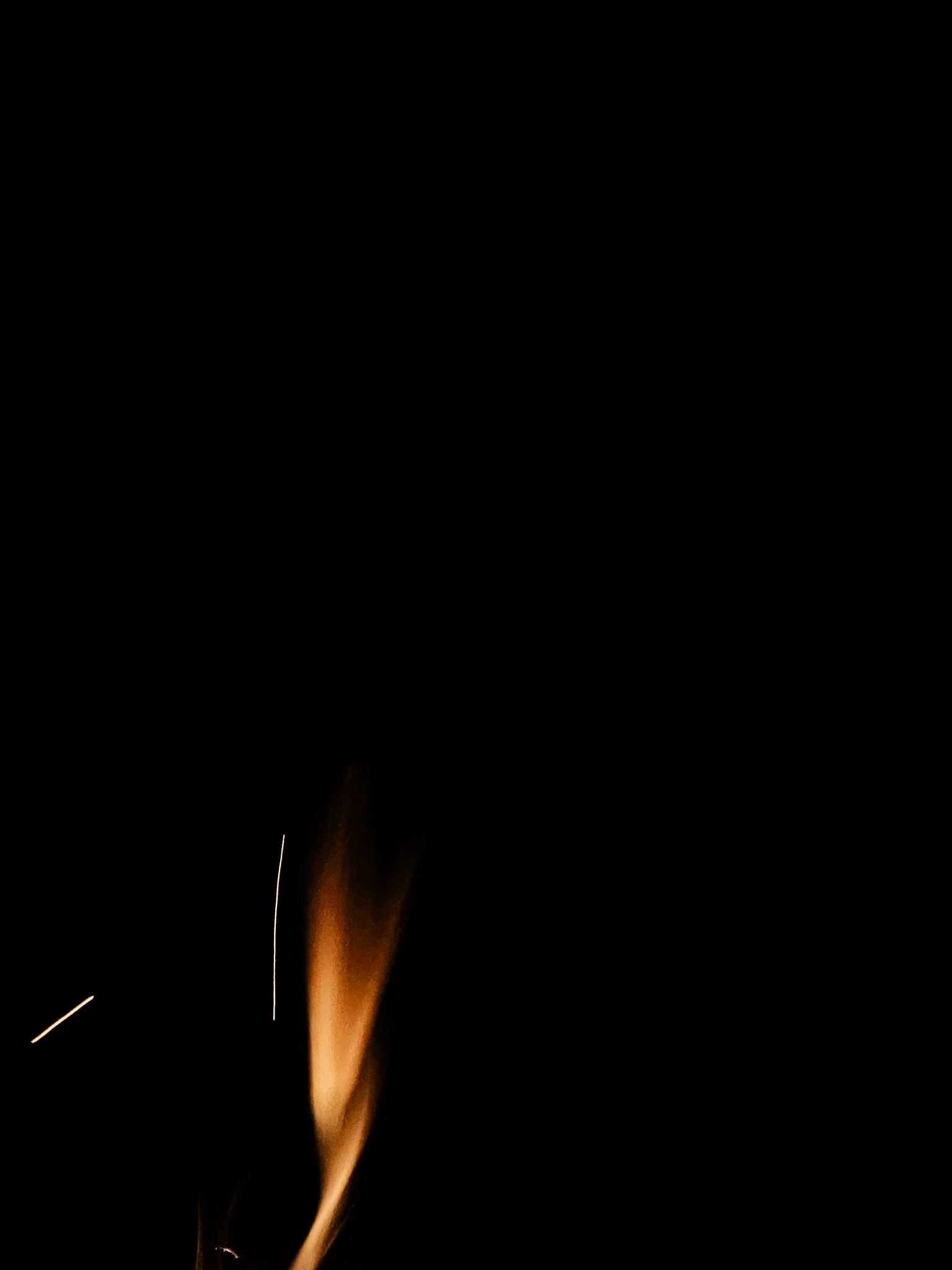 Close-up of a sparkler emitting sparks and glowing bright against a dark night backdrop.