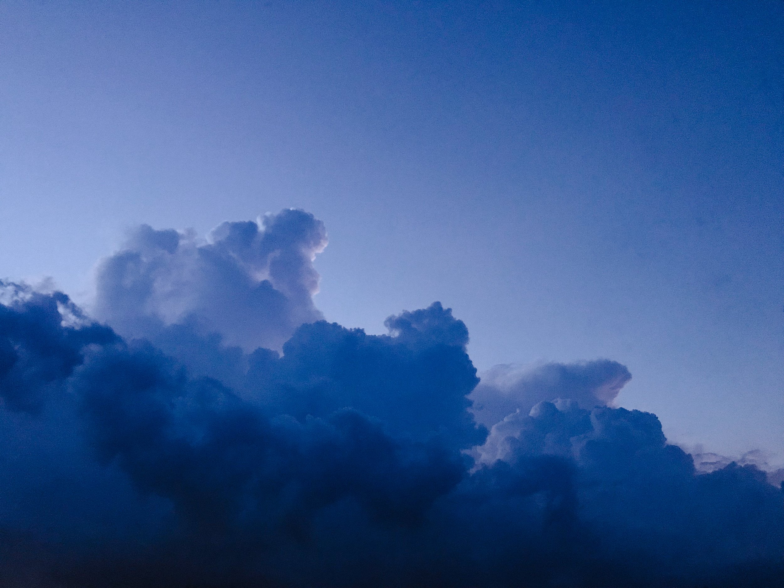 A sky with a gradient of blue hues, featuring a few scattered clouds near the bottom of the image.