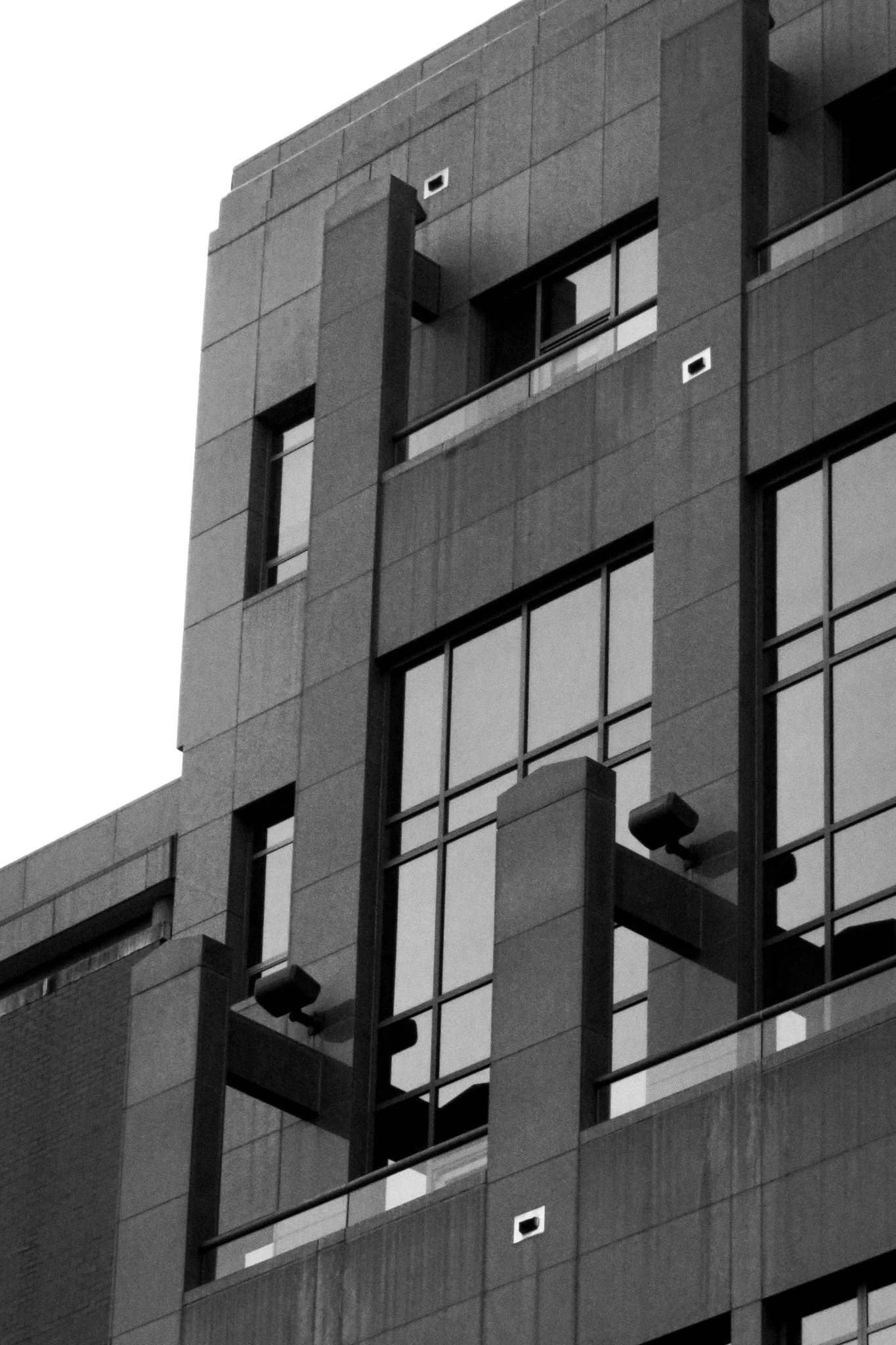 Black and white photo of a modern multi-story building with large glass windows and concrete structural elements.