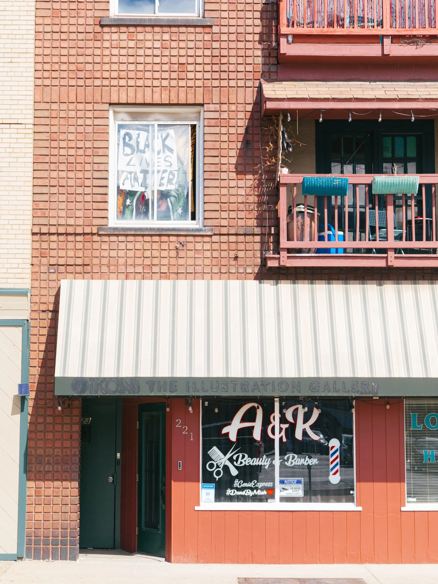 The storefront of a beauty and barber shop with a sign that reads '#GenieExpress #DameByMiah' and a barber pole hanging outside.